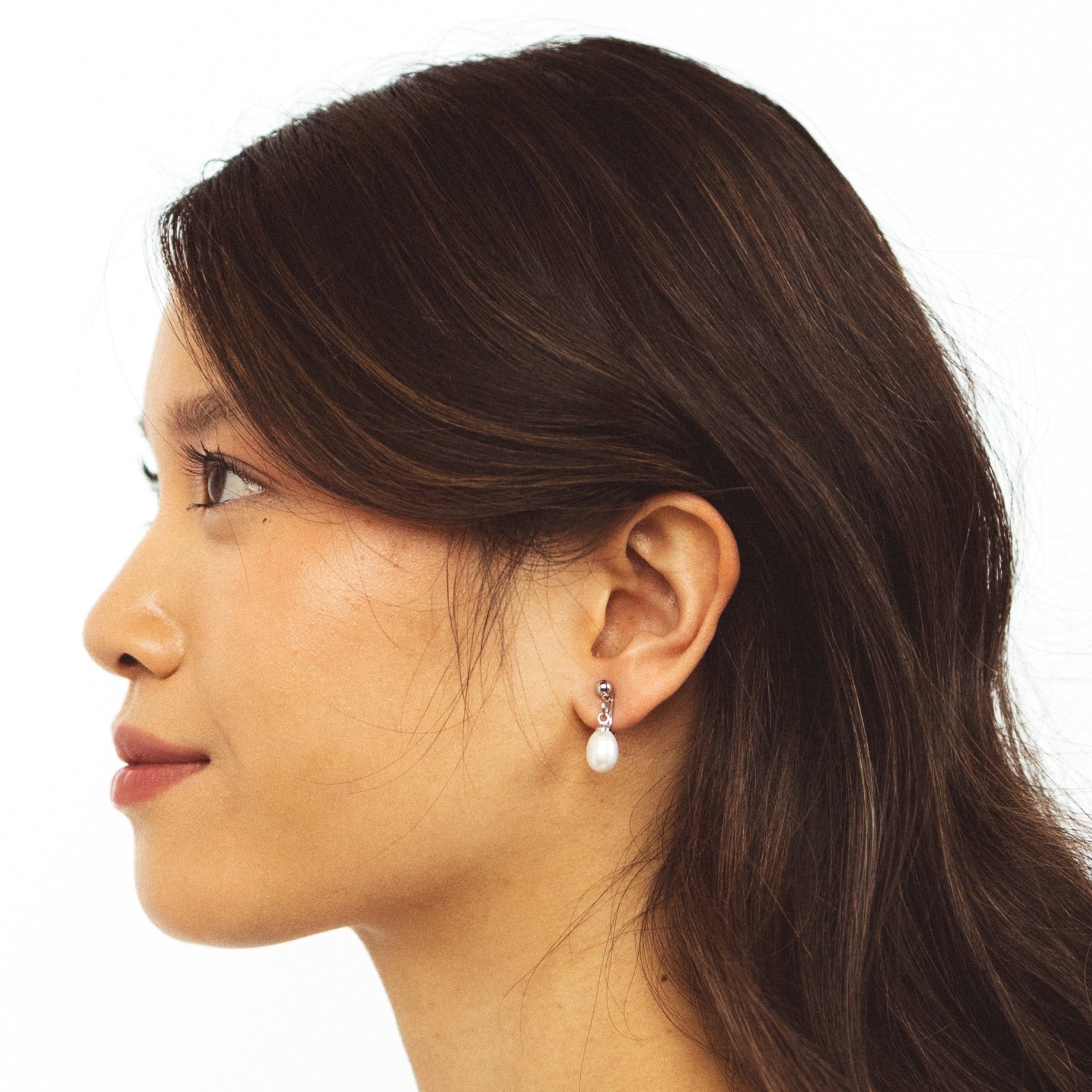 A model wearing the Elio Clip On Earrings. Designed for all ear types, these elegant earrings provide a secure hold for up to 24 hours. Enjoy unparalleled comfort and style, perfect for those with sensitive or stretched ears. Upgrade your style effortlessly with Elio.
