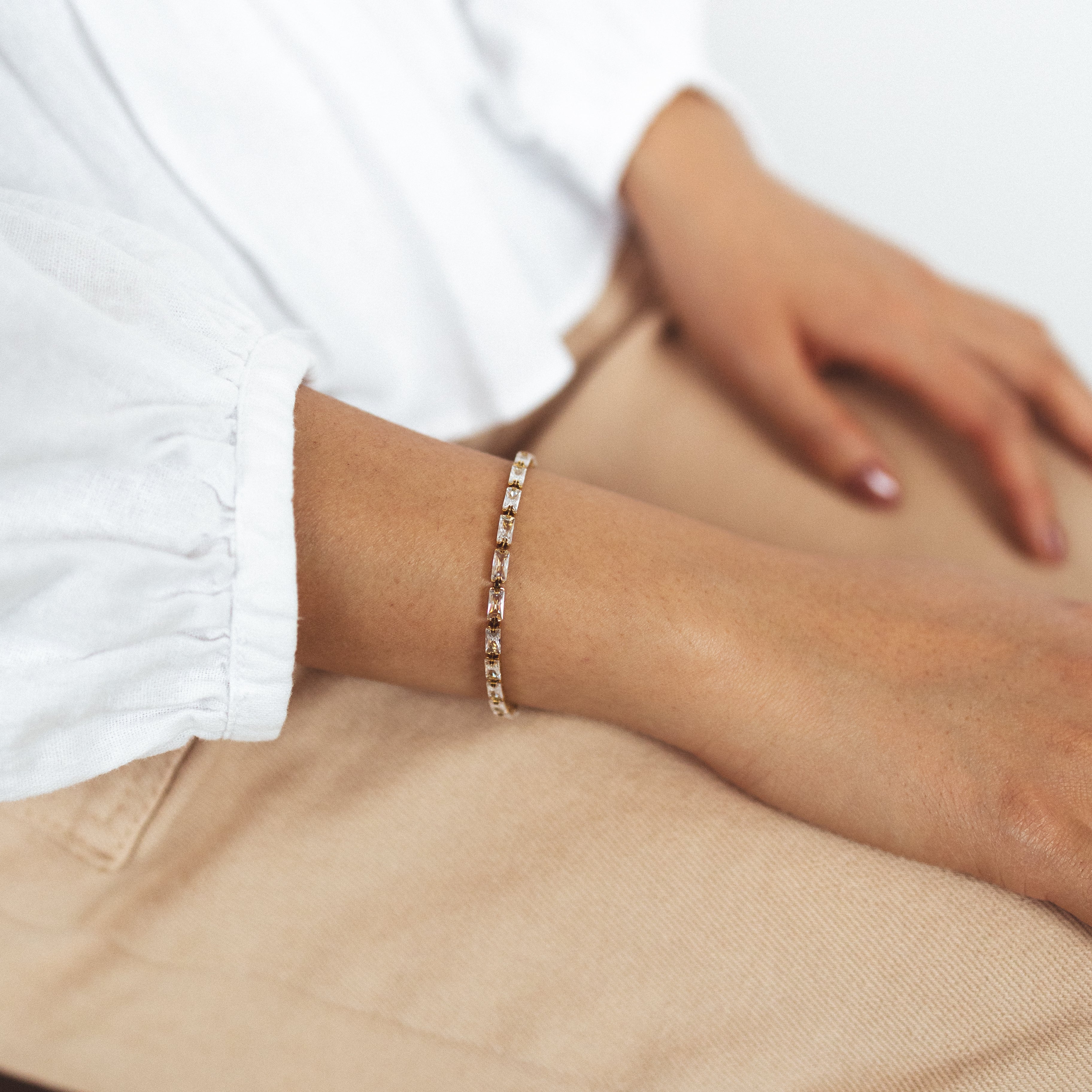 A model wearing the stunning Elizabeth Bracelet - a perfect blend of fashion and function. With adjustable sizing and 18K gold plated stainless steel, it's both versatile and durable. Enjoy its non-tarnish, water-resistant, and allergy-free properties. Elevate any look with this must-have accessory.