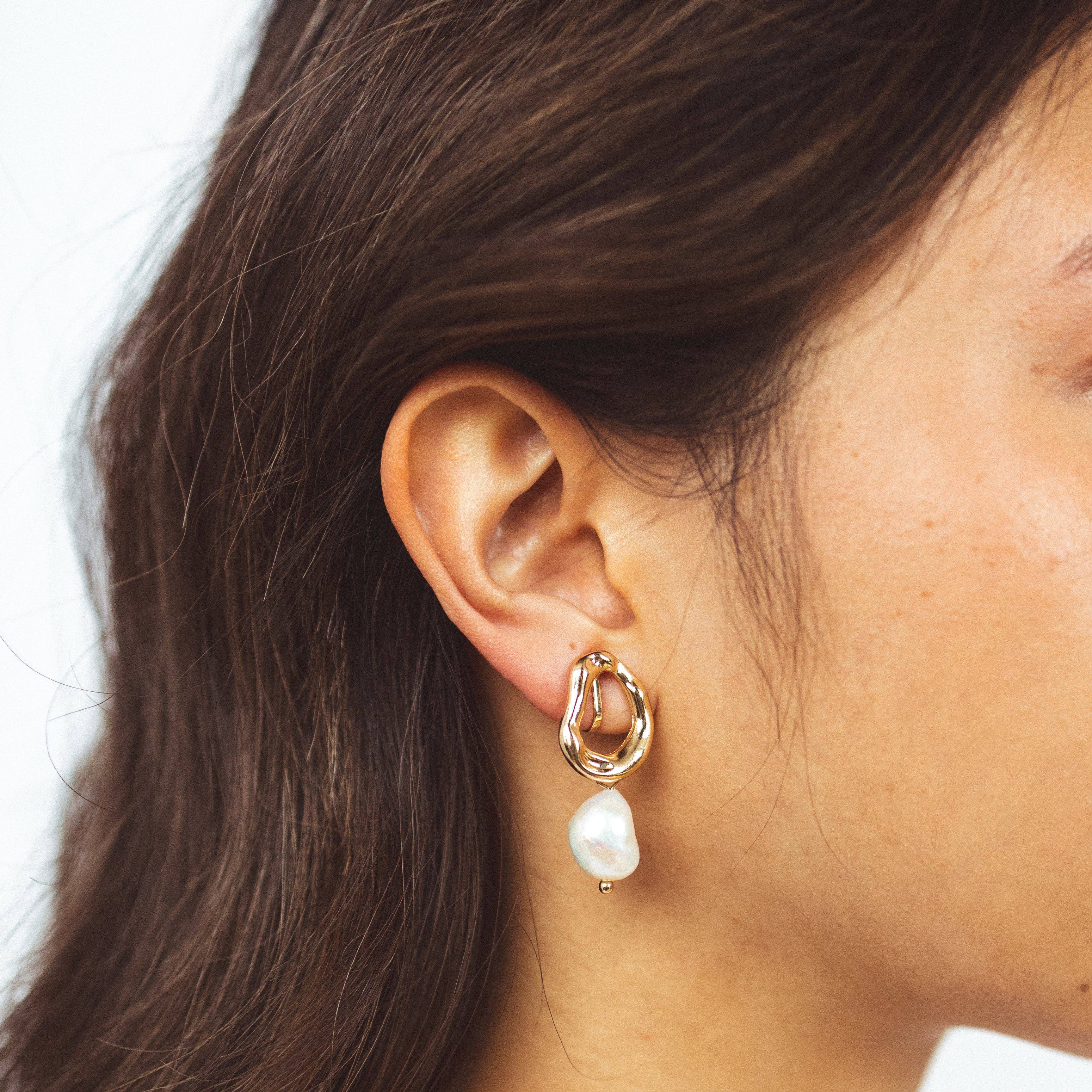 A model wearing the Ella Clip On Earrings. Perfect for sensitive or stretched ears, they provide a 24-hour hold and adjustable fit for unmatched comfort. Effortlessly add a touch of elegance to your look.