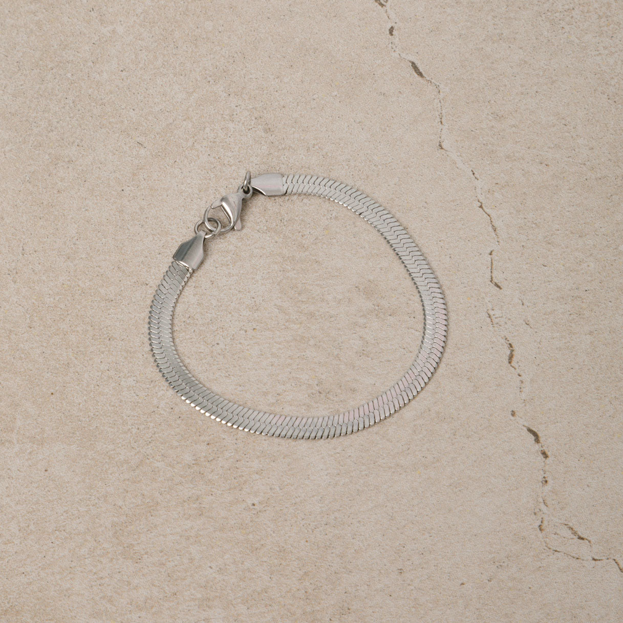 Image of the Herringbone Chain Bracelet in Silver is crafted with stainless steel and measures 18cm long and 5mm wide. It is also non-tarnish and water resistant.