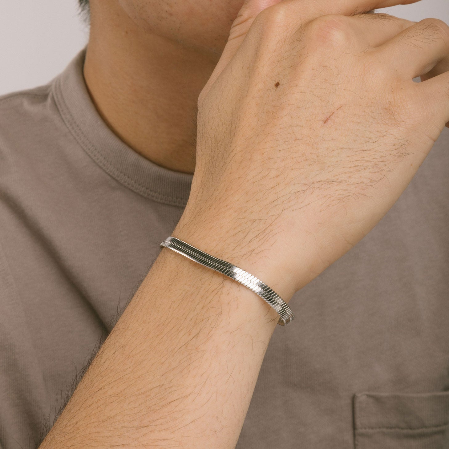 A model wearing the Herringbone Chain Bracelet in Silver is crafted with stainless steel and measures 18cm long and 5mm wide. It is also non-tarnish and water resistant.