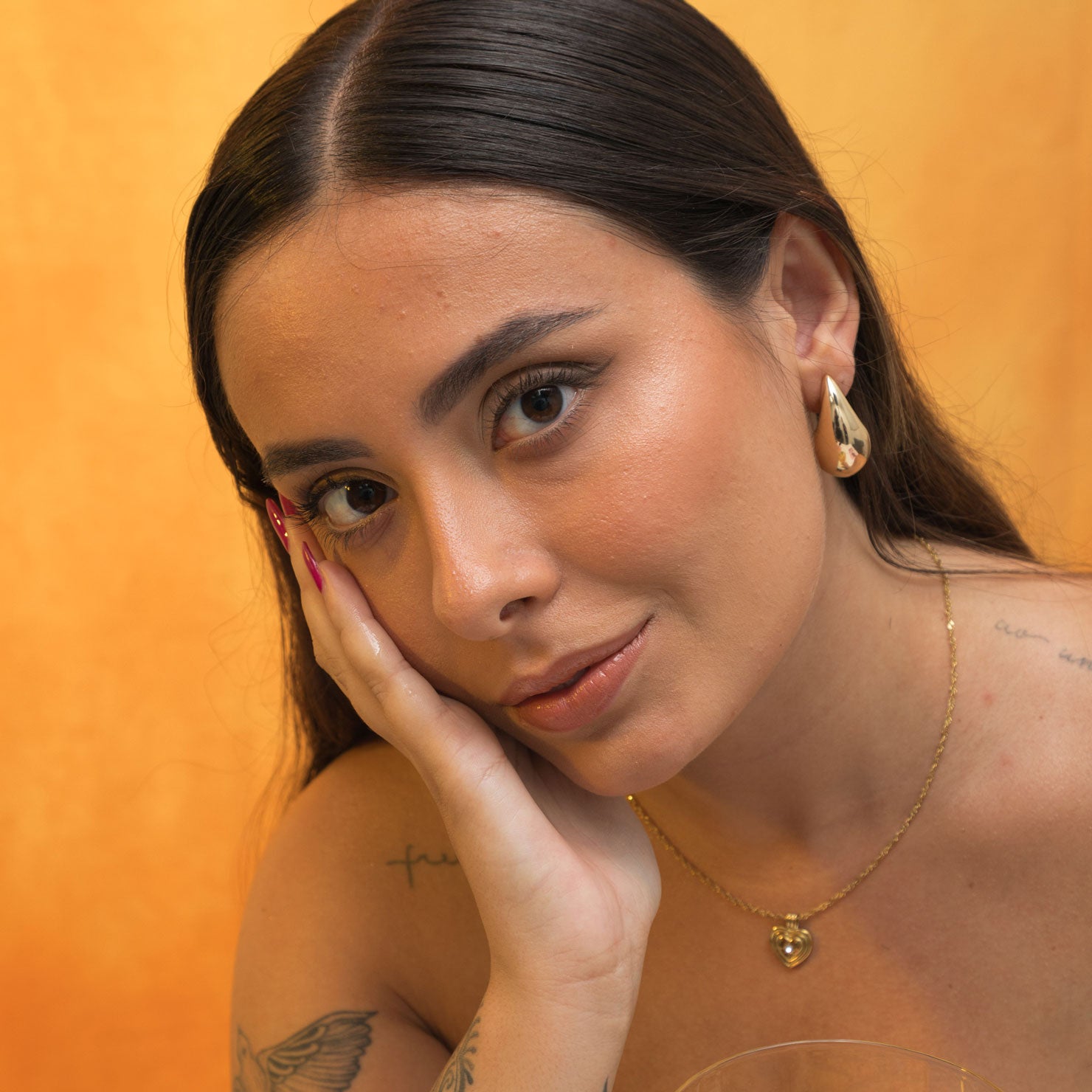 A model wearing the Isla Clip On Earrings in Gold feature a secure screwback closure that fits all ear types, providing an average comfortable wear duration of 8 - 12 hours. The hold strength is strong and you can manually adjust the earrings to your ear size. Constructed of gold toned copper alloy, this item is a single pair.