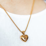 A model wearing the Jude Heart Necklace is expertly crafted from 18K Gold Plated Stainless Steel, resulting in a durable and water-resistant accessory. Its adjustable chain allows for a customized fit. Elegant and functional, this single necklace is a must-have for any jewelry collection.
