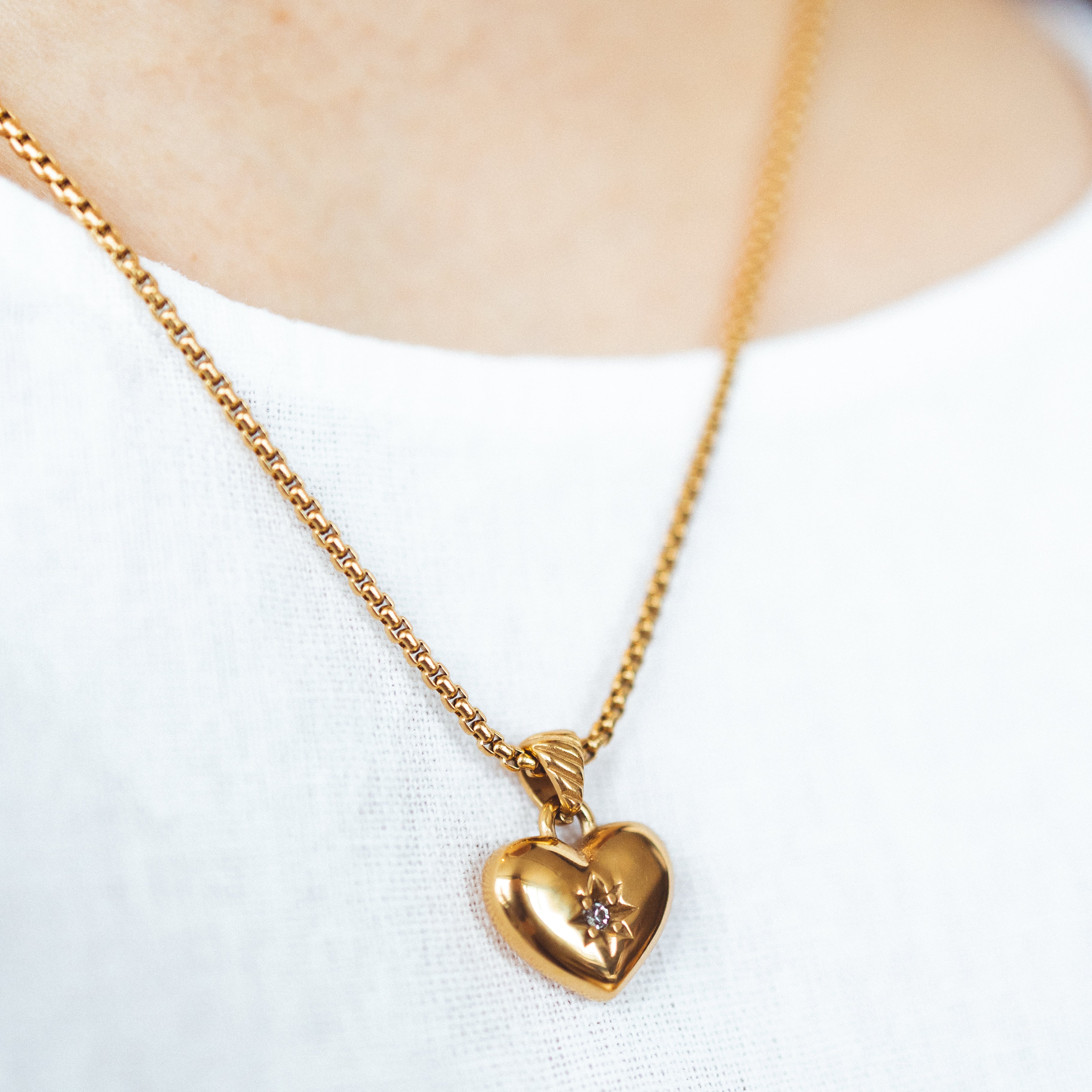 A model wearing the Jude Heart Necklace is expertly crafted from 18K Gold Plated Stainless Steel, resulting in a durable and water-resistant accessory. Its adjustable chain allows for a customized fit. Elegant and functional, this single necklace is a must-have for any jewelry collection.