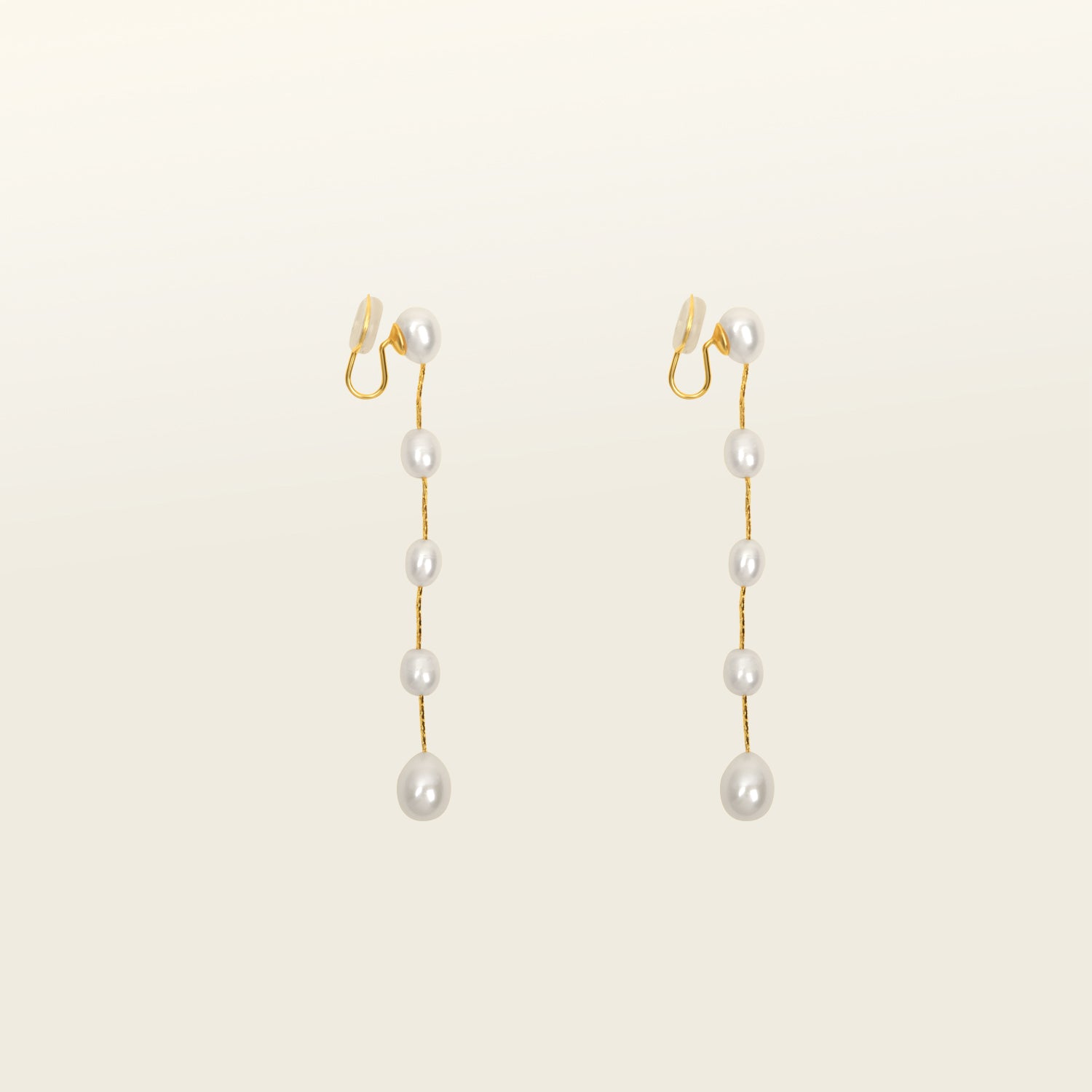 Image of the Lune Pearl Clip-On Earrings in Gold feature a unique, secure mosquito coil clasp. They are ideal for all ear types, from thick and large ears to sensitive and small. With medium hold strength, the earrings can be comfortably worn up to 24 hours and easily adjusted. Crafted with freshwater pearls, each pair may display natural variations in size and color. Materials include freshwater pearl and 18K gold-plated stainless steel.