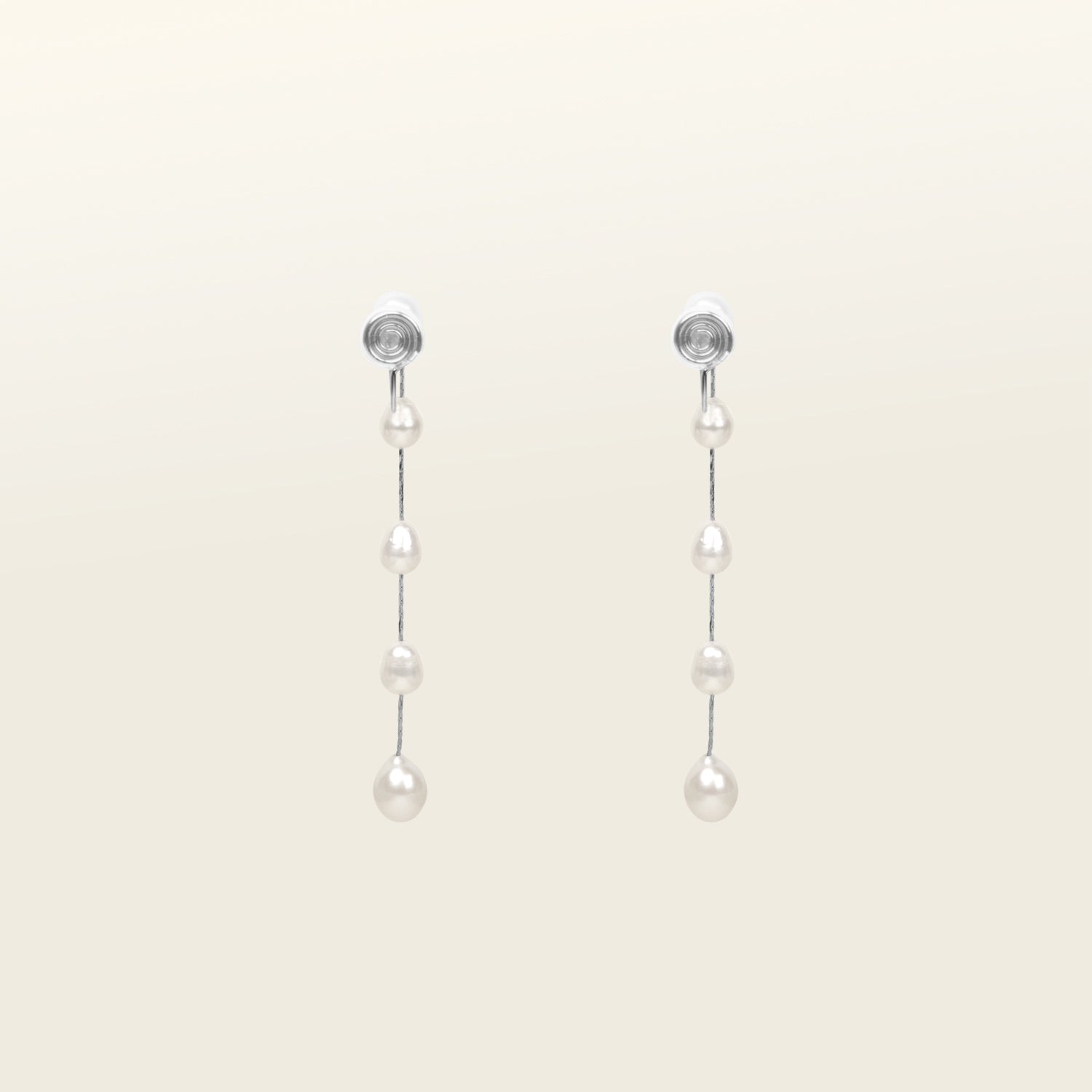 Image of the Lune Pearl Clip-On Earrings in Silver with ease and comfort. Their Mosquito Coil Clip-Ons feature a medium secure hold that can be adjusted to any ear size, shape, and sensitivity-level. Crafted from Freshwater Pearls, each set exhibits its own unique color and size for a one-of-a-kind look. Long-lasting design ensures it can be worn for up to 24 hours with ease.