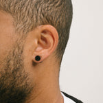 A model wearing the Magnetic Stud Clip On Earring in Black provides secure hold for up to 6 to 8 hours of comfortable wear for all ear types. It is made of stainless steel and one pair is included. Adjustment is not possible with this item.