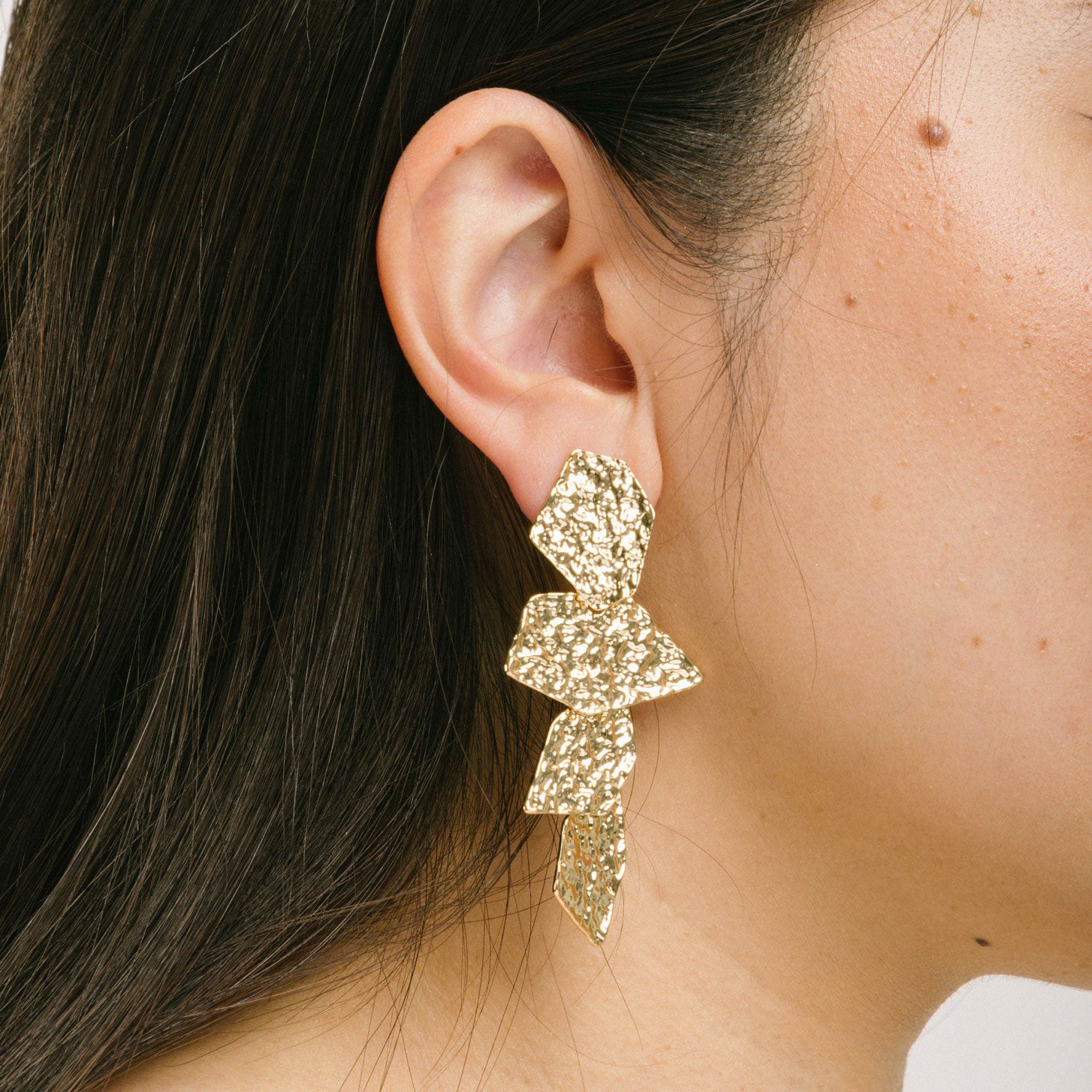A model wearing the Manhattan Drop Clip On Earrings in Gold provide a secure and comfortable fit for any ear type. The padded clip-on design features a zinc and copper alloy construction, and lasts approximately 8-12 hours. As the earring pairs are non-adjustable, each purchase contains a single pair.