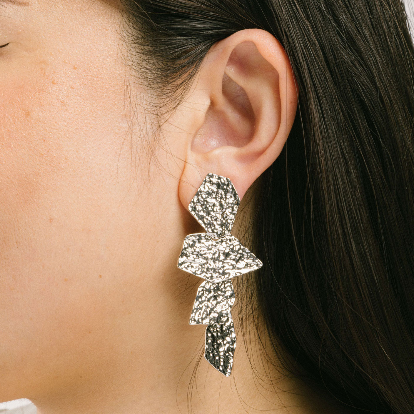 A model wearing the Manhattan Drop Clip On Earrings in Silver provide a secure and comfortable fit for any ear type. The padded clip-on design features a zinc and copper alloy construction, and lasts approximately 8-12 hours. As the earring pairs are non-adjustable, each purchase contains a single pair.
