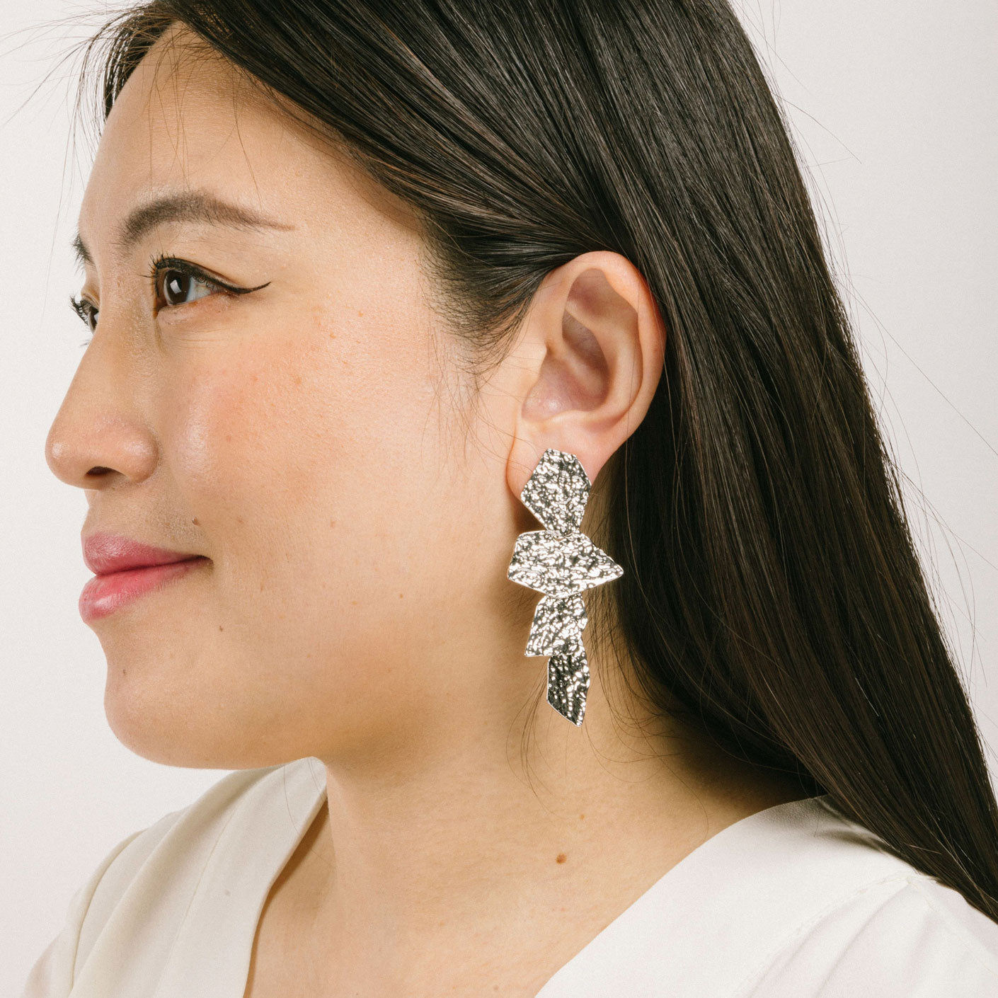 A model wearing the Manhattan Drop Clip On Earrings in Silver provide a secure and comfortable fit for any ear type. The padded clip-on design features a zinc and copper alloy construction, and lasts approximately 8-12 hours. As the earring pairs are non-adjustable, each purchase contains a single pair.