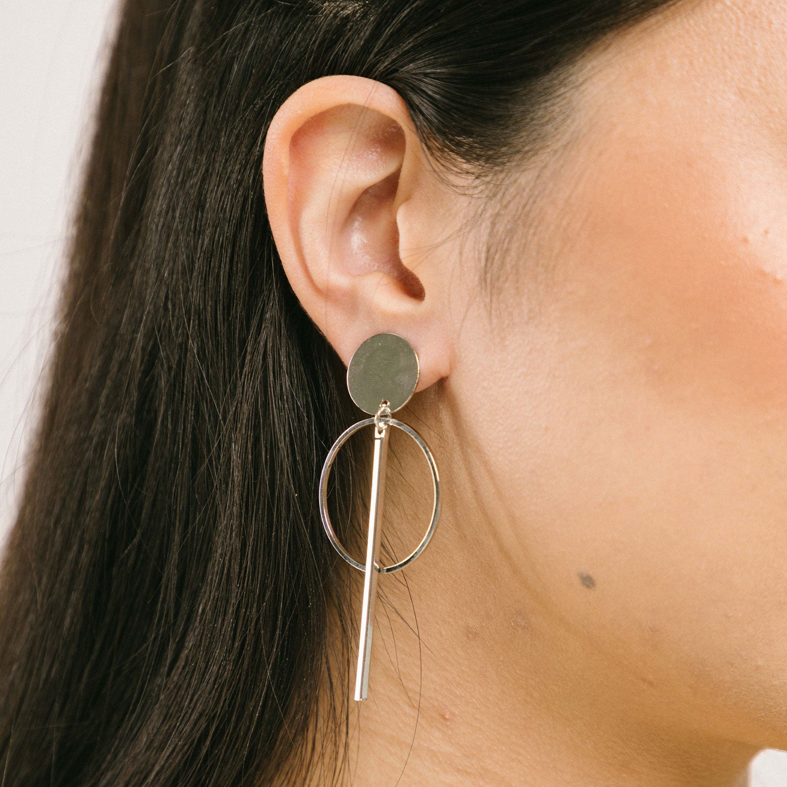 A model wearing the Melissa Clip-On Earrings offer a secure hold, with an average comfortable wear duration of 8-12 hours. The closure type is padded for a secure fit that accommodates all ear types, including thick/large ears, sensitive ears, small/thin ears, and stretched/healing ears. Constructed from gold tone/silver tone plated zinc alloy, each pair includes removable rubber padding.