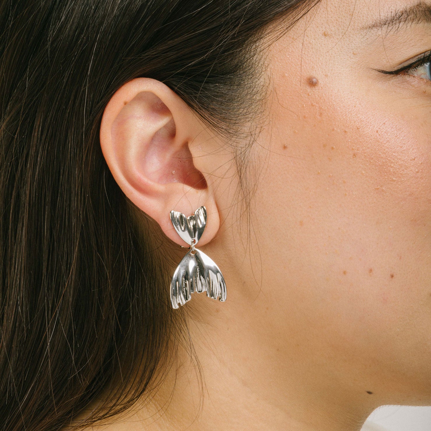 A model wearing the Mermaid Tail Clip On Earrings crafted in Silver Tone Zinc Alloy provide a secure hold for 8 to 12 hours. Padded Clip-On style is ideal for all ear types, and the earrings come as one pair with removable rubber padding. No adjustments possible.