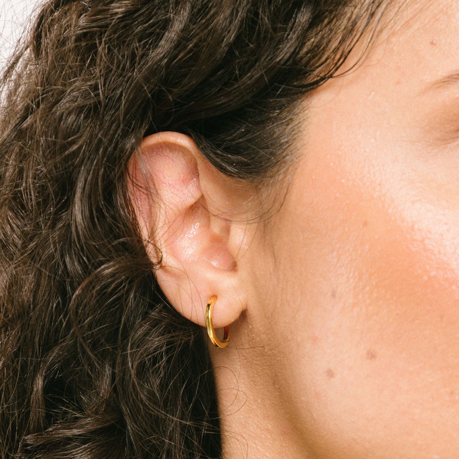 A model wearing the Mini Hoop Clip-On Earrings feature a sliding spring closure and are best suited for those with smaller or thinner ear lobes. On average, each pair can be comfortably worn for up to 4 hours, and provide a very secure hold that automatically adjusts to the ear thickness for a perfect fit. Crafted with stainless steel, each pair is sold individually.