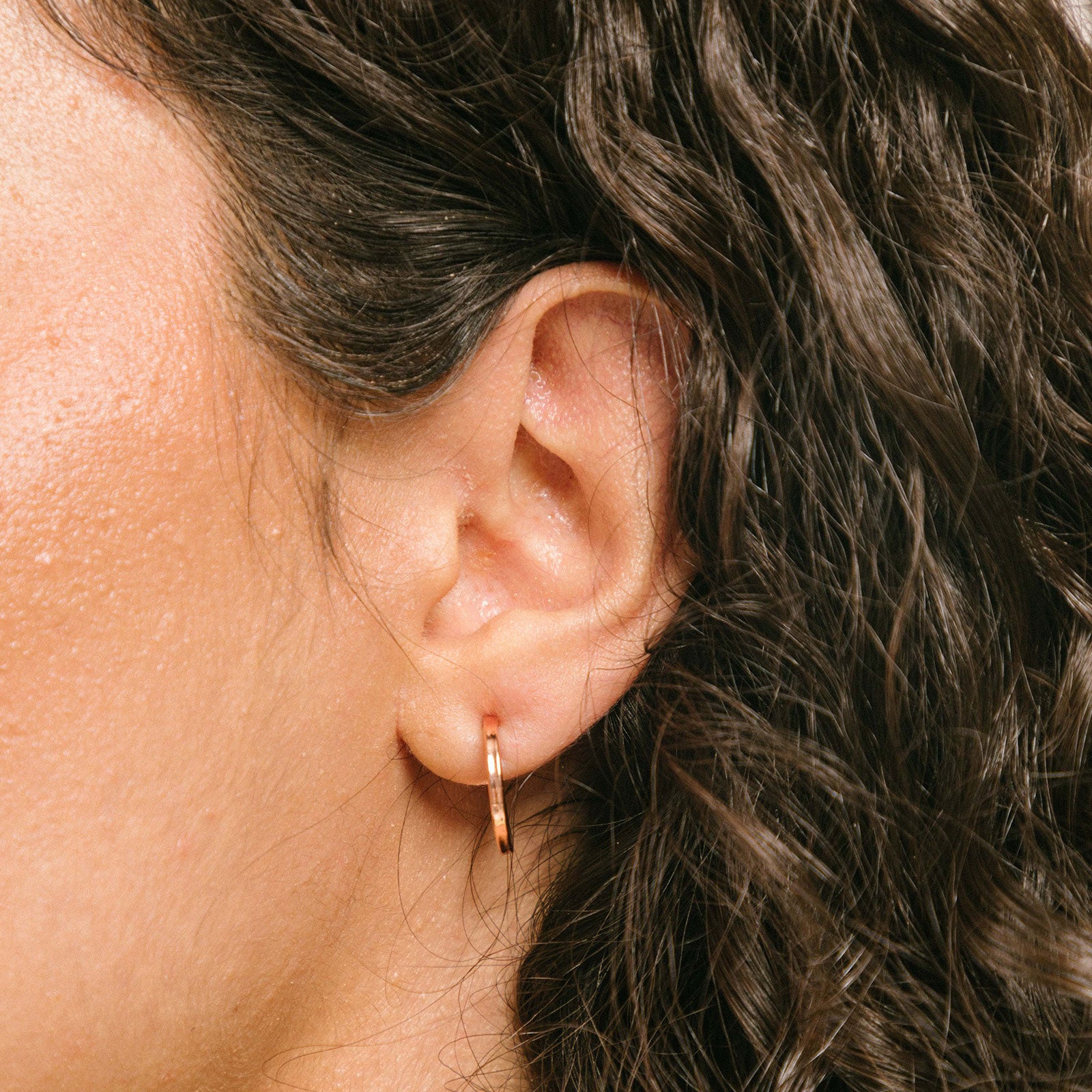 A model wearing the Mini Hoop Clip-On Earrings feature a sliding spring closure and are best suited for those with smaller or thinner ear lobes. On average, each pair can be comfortably worn for up to 4 hours, and provide a very secure hold that automatically adjusts to the ear thickness for a perfect fit. Crafted with stainless steel, each pair is sold individually.