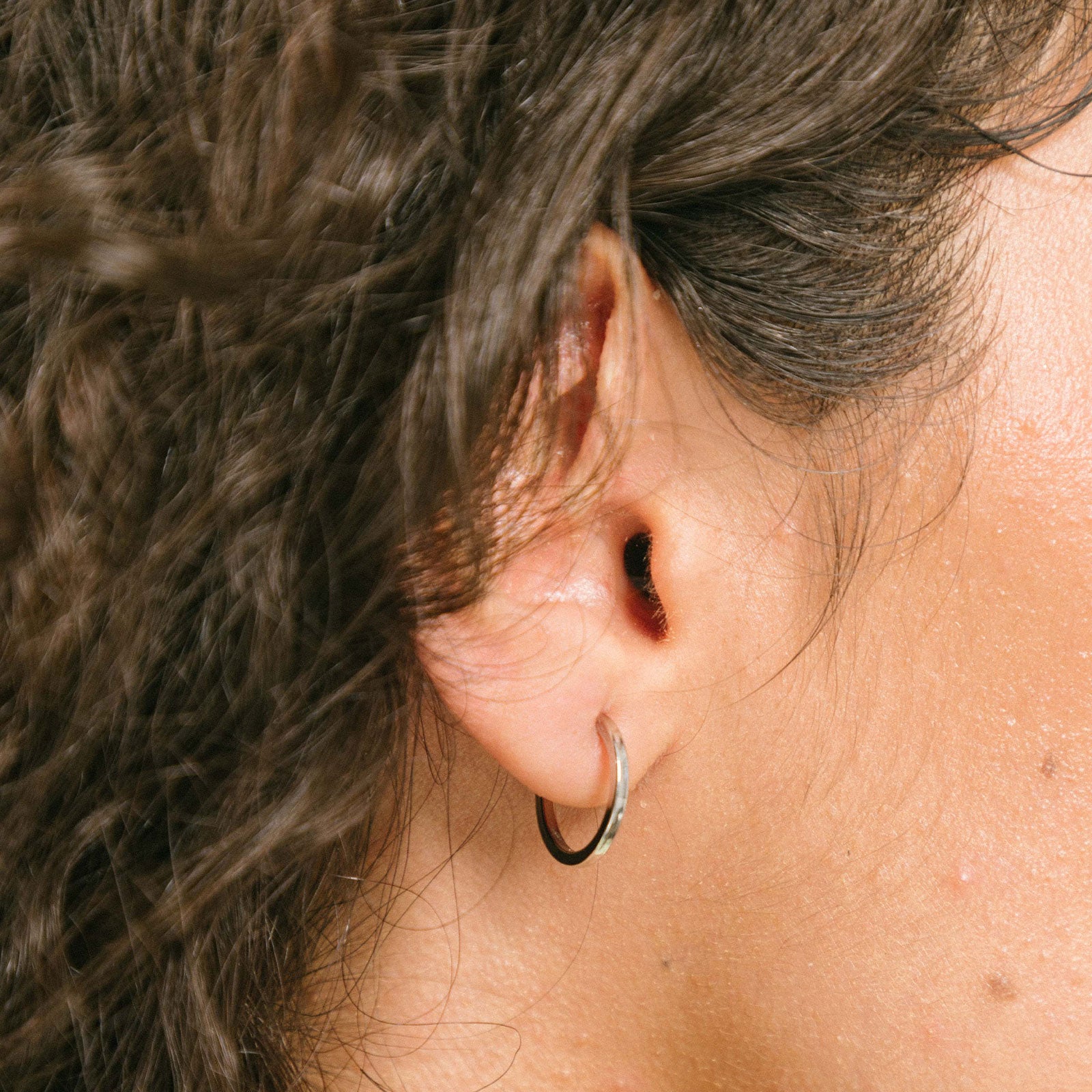 A model wearing the Mini Hoop Clip-On Earrings feature a sliding spring closure and are best suited for those with smaller or thinner ear lobes. On average, each pair can be comfortably worn for up to 4 hours, and provide a very secure hold that automatically adjusts to the ear thickness for a perfect fit. Crafted with stainless steel, each pair is sold individually.