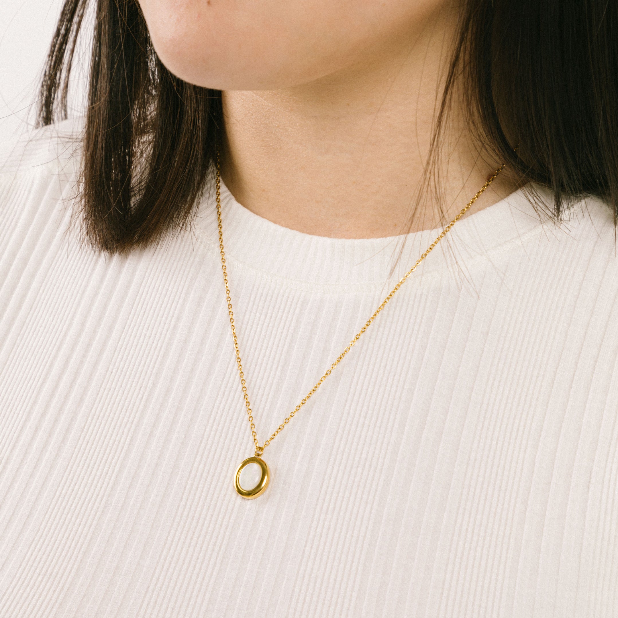 A model wearing the Mother of Pearl Pendant Necklace is crafted from 18K Gold Plated over Stainless Steel and is both non-tarnish and waterproof - perfect for everyday wear. For an added touch, pair the necklace with its sister Celestial Ring for the complete, stunning look.