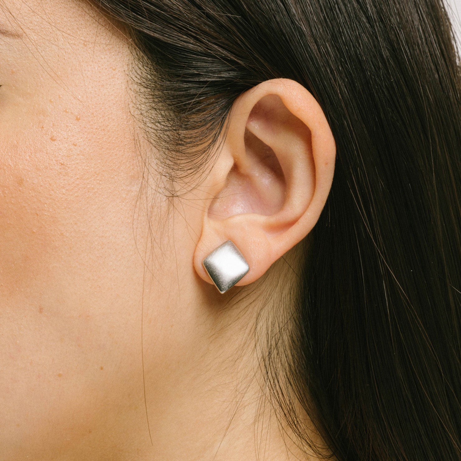 A model wearing the Negroni Clip On Earrings feature a Mosquito Coil Clip-On design, making them suitable for all ear types. Keep them on for up to 24 hours without discomfort, thanks to medium-strength secure hold and adjustable padding. Crafted from a Silver Toned Copper Alloy, each purchase contains one pair.