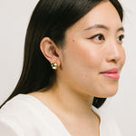 A model wearing the Olive Clip On Earrings feature a Mosquito Coil Clip-On closure type, ideal for all ear types. Average comfortable wear duration is 24 hours, with a medium secure hold. These earrings are adjustable; gently squeeze the padding forward once they are on the ear. Materials are gold tone copper. Please note, item is only one pair.