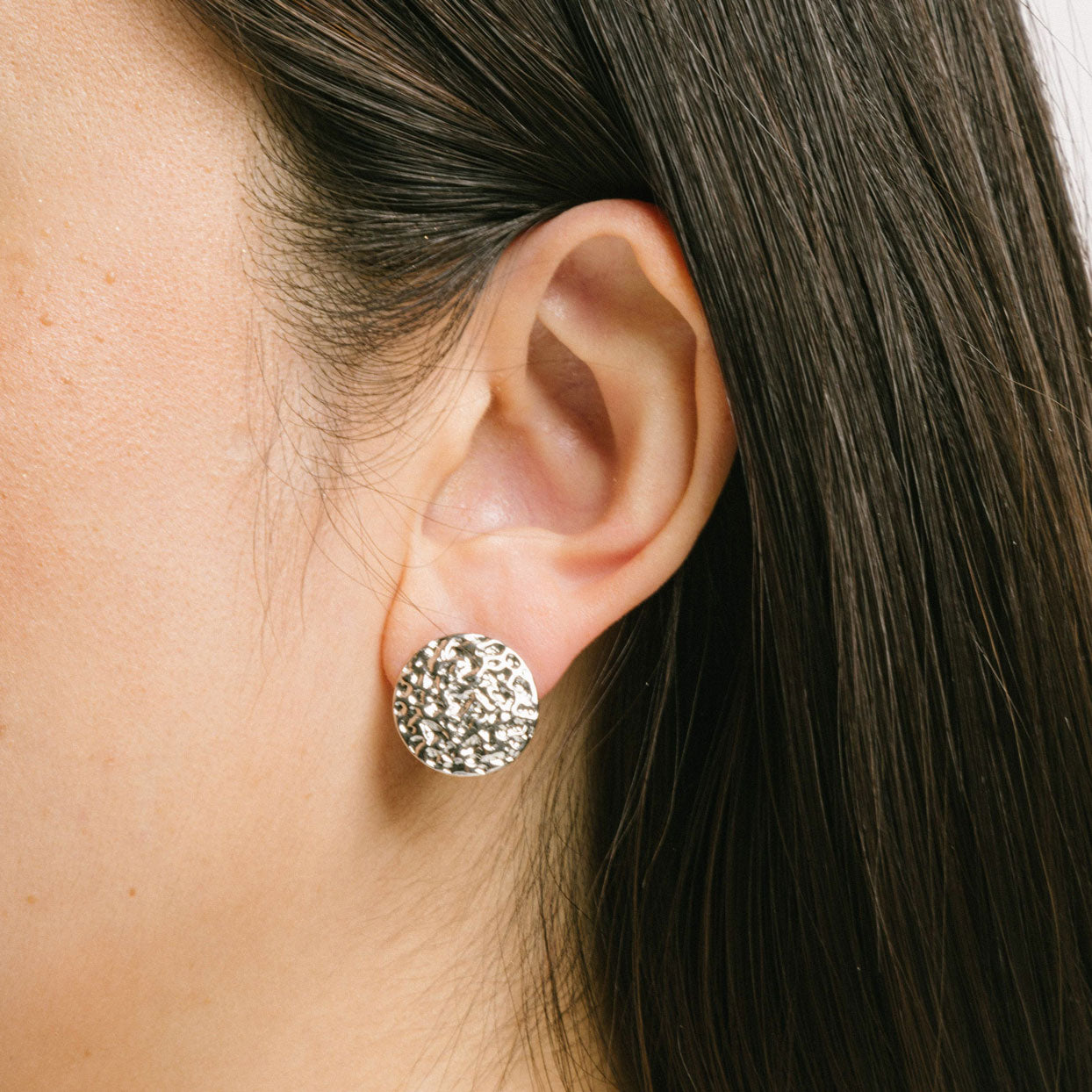 A model wearing the Paloma Clip-On Earrings in Silver provide a secure fit that is perfect for all ear types, including thick/large ears, sensitive ears, small/ thin ears, and stretched/healing ears. These earrings are crafted with a copper alloy and are free of lead and nickel. Their removable rubber padding ensures comfortable wear for up to 12 hours. This package contains one pair of earrings.