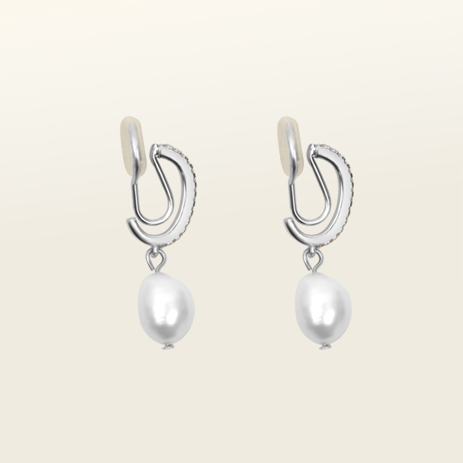 Image of the Pearl Pavé Huggie Clip-On Earrings in Silver feature a mosquito coil clip-on closure and are suitable for all ear types including thick/large, sensitive, small/thin and stretched/healing ears. For a secure but comfortable hold, they can be worn for up to 24 hours and can be adjusted with a gentle squeeze of the padding. Made with Freshwater Pearls and Silver Plated Brass, each pair has natural variations in size and colour.