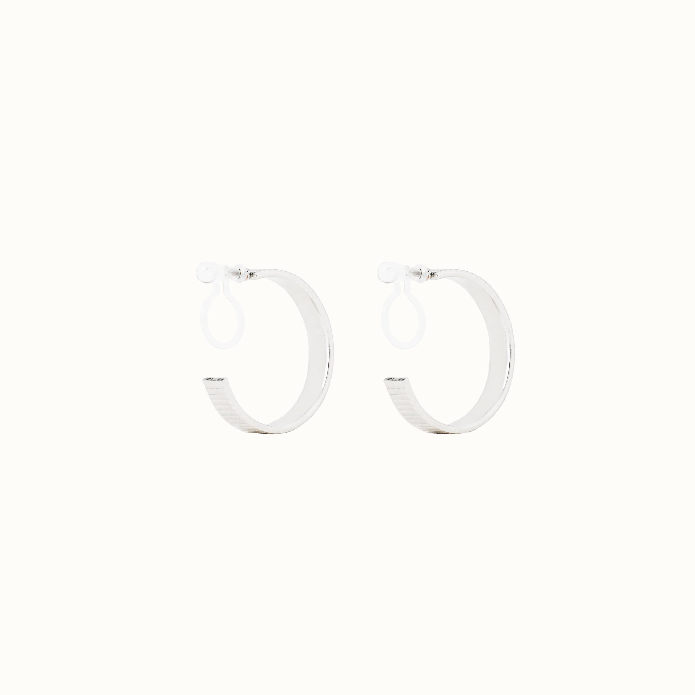 Image of the Pleated Hoop Clip On Earrings in Silver offer a resin clip-on closure for a secure and comfortable fit for a variety of ear sizes and sensitivities. With an average wear duration of 8-12 hours, these earrings are perfect for all-day wear. Please note that this listing is for a single pair.