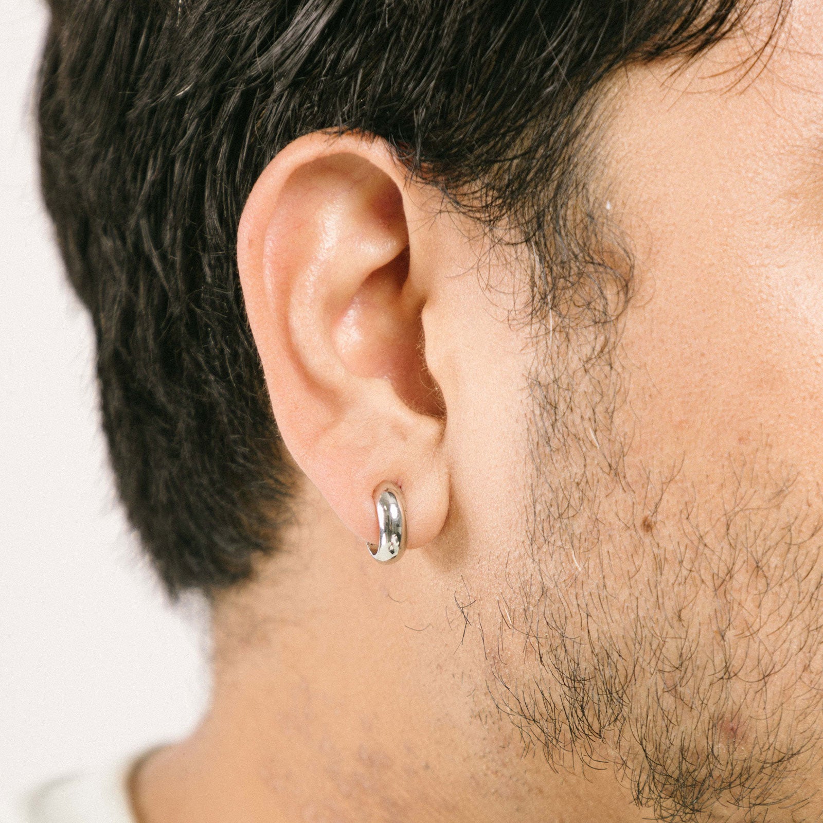 A model wearing the Simple Silver Huggie Clip-On Earrings provide a medium secure hold, making them perfect for all ear types. With adjustable padding for extra comfort, these earrings can be worn for up to 24 hours with ease. 