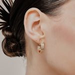 A model wearing the Speckled Hoop Clip On Earrings in Gold offer versatility and comfort for a range of ear sizes and sensitivities. With a medium secure hold, you can confidently wear them for 8-12 hours. Sold as a pair.