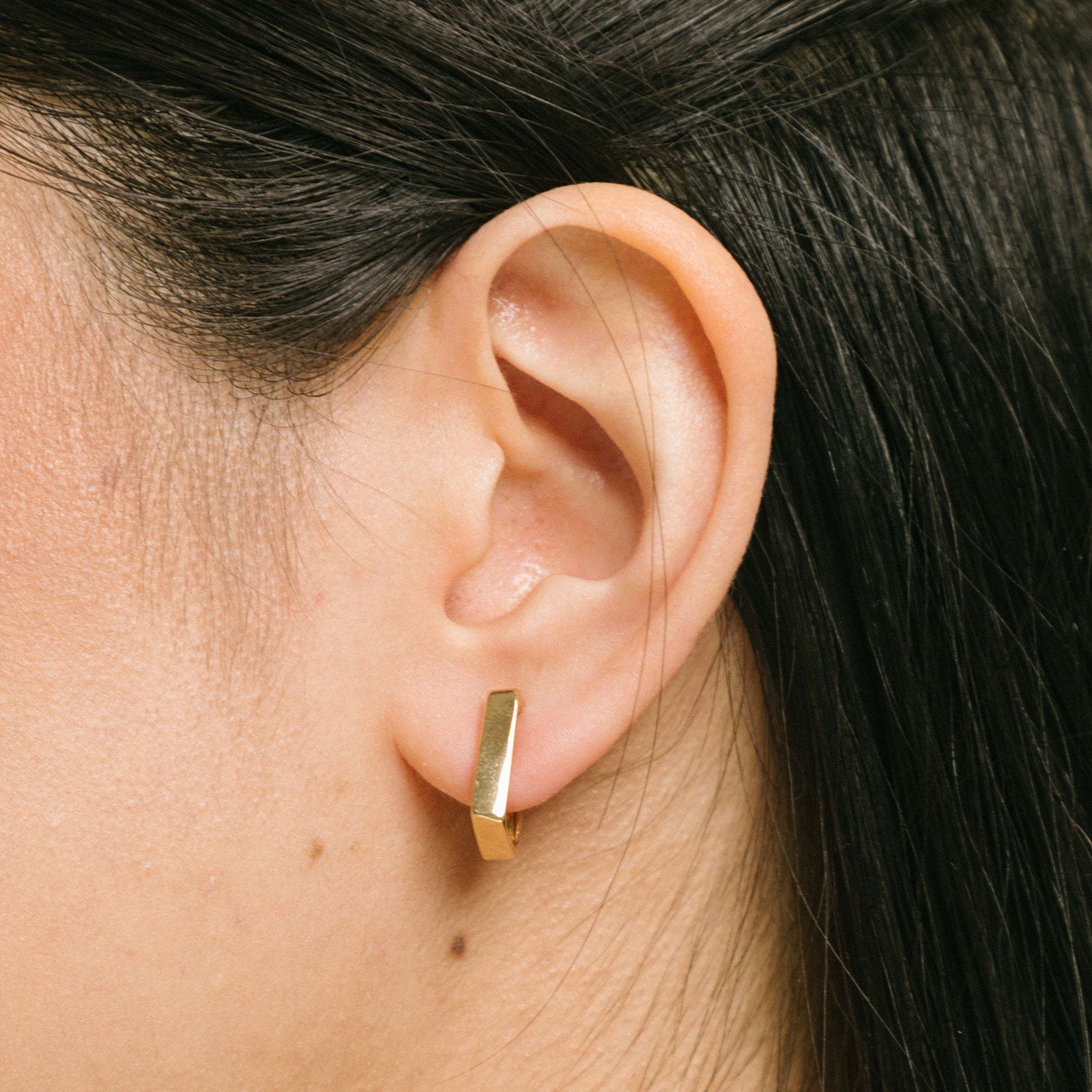 A model wearing our Classic Square Huggie Hoop Clip-On Earrings - 14k Gold plated metal alloy, non-tarnish, and water-resistant. Modern square clip-on design with mosquito coil closure and paddings for a secure, comfortable fit all day.
