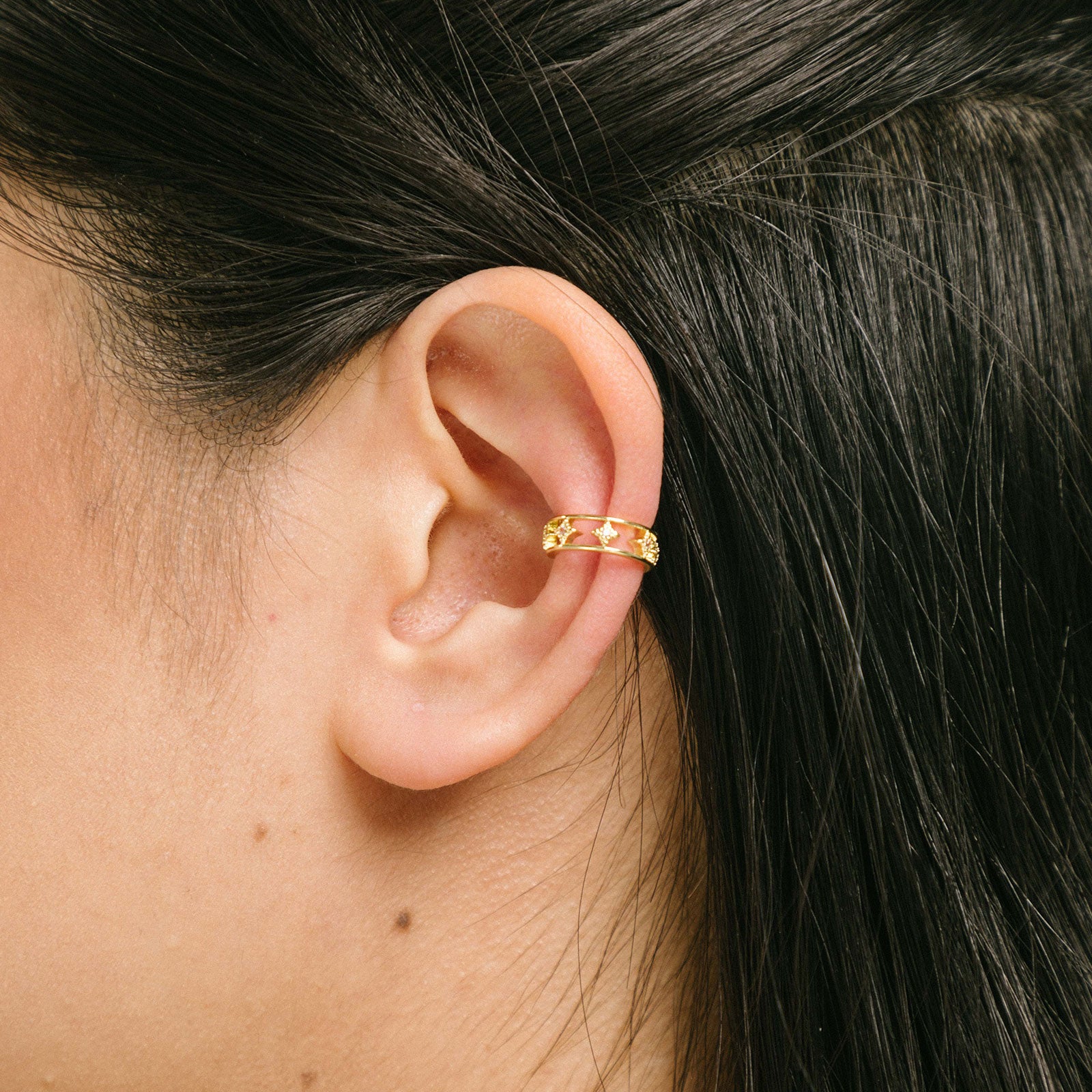A model wearing our Star Ear Cuff, a sleek and modern accessory crafted from gold-tone plated zinc alloy, adorned with sparkling rhinestones and charming stars. This versatile piece is designed to elevate the style of both women and men, making it the perfect choice to showcase your fashionable side.