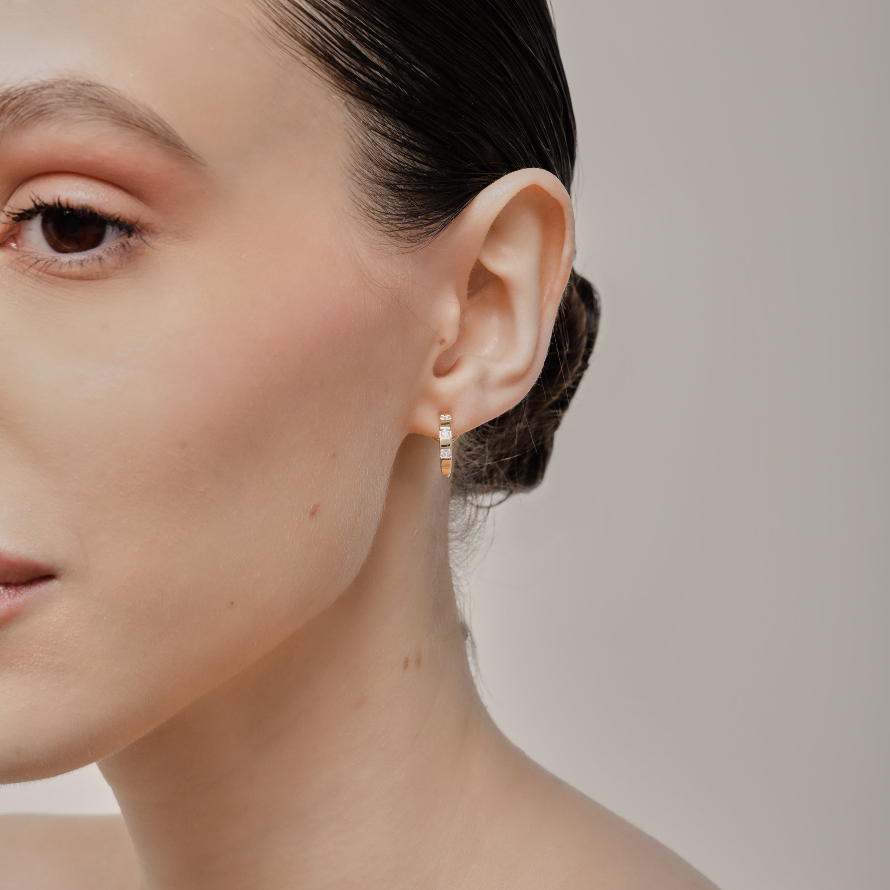 A model wearing the Sydney Pave Clip On Earrings in Gold for those with thick, sensitive, small, stretched, or keloid prone ears. Its medium secure hold and adjustable padding make it a comfortable and stylish choice. Made with high-quality gold tone copper alloy.