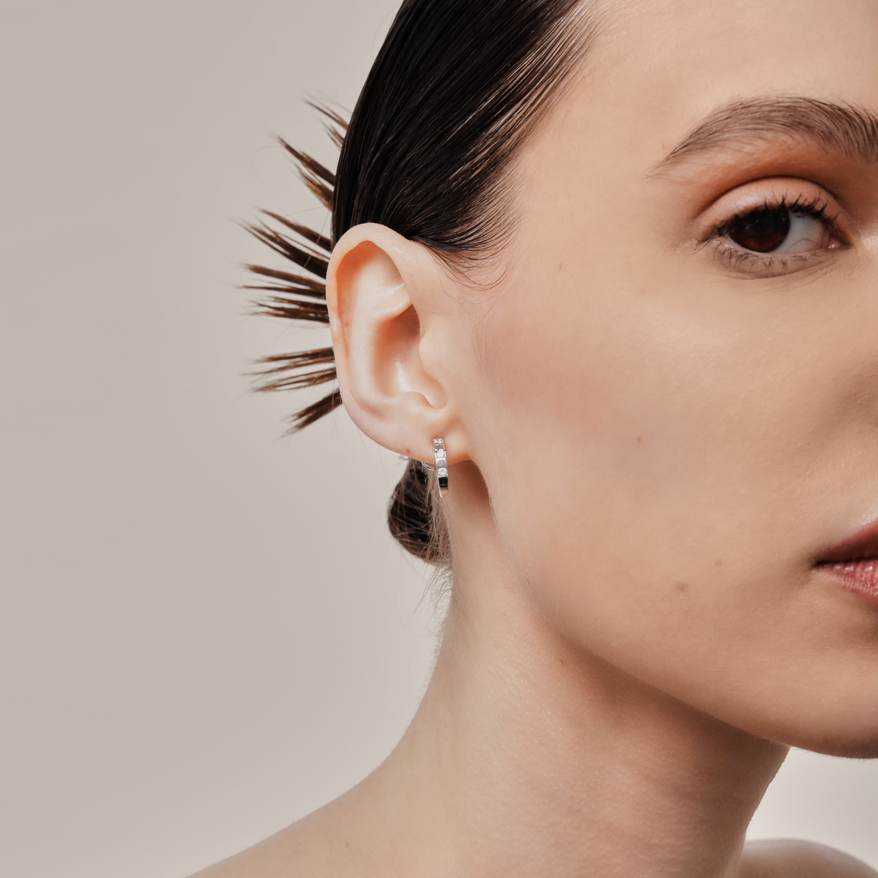 A model wearing the Sydney Pave Clip On Earrings in Silver for those with thick, sensitive, small, stretched, or keloid prone ears. Its medium secure hold and adjustable padding make it a comfortable and stylish choice. Made with high-quality silver tone copper alloy.