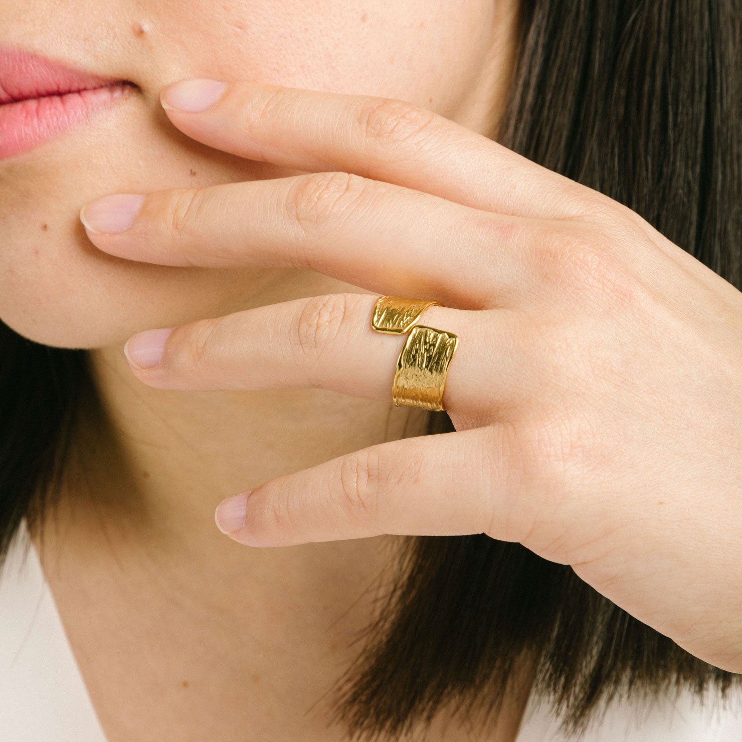 A model wearing the Textured Curl Ring in Gold is adjustable between sizes 7-10, crafted using 14K Gold Plated Stainless Steel for durability and resistance to tarnish, water, and lead, nickel, and cadmium. Please note that only one ring is included.