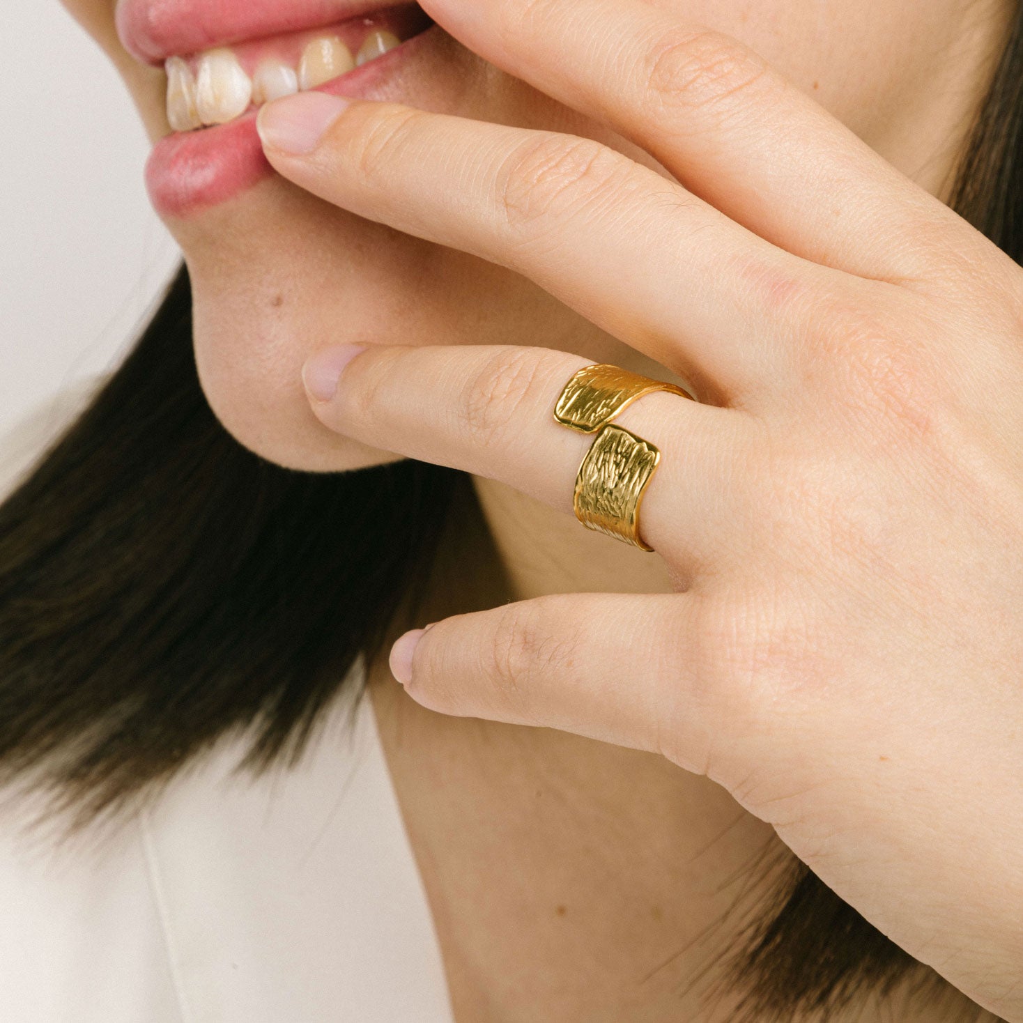 A model wearing the Textured Curl Ring in Gold is adjustable between sizes 7-10, crafted using 14K Gold Plated Stainless Steel for durability and resistance to tarnish, water, and lead, nickel, and cadmium. Please note that only one ring is included.