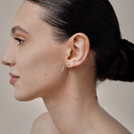 A model wearing the Tia Hoop Clip On Earrings in Silver are a must-have accessory. With a resin clip-on closure, they offer a secure hold for 8-12 hours of comfortable wear. Perfect for sensitive or small ears, and even those with thick or large ears. Please note, one pair included.