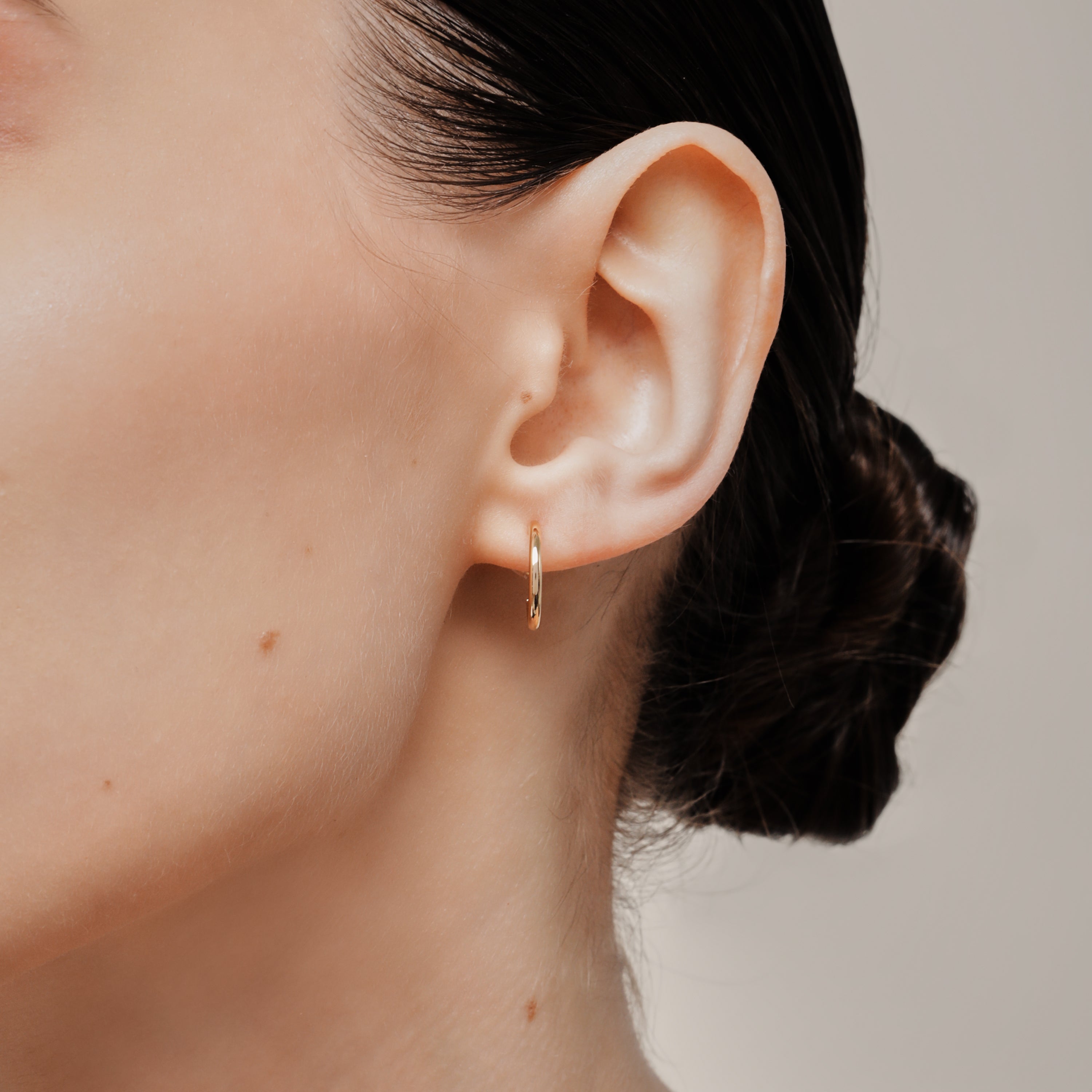 A model wearing the Tiny Hoop Clip On Earrings in Gold offer a Mosquito Coil Clip-On Closure, designed for comfort and versatility. Perfect for various ear types, they provide a secure hold and comfortable wear for 24 hours.