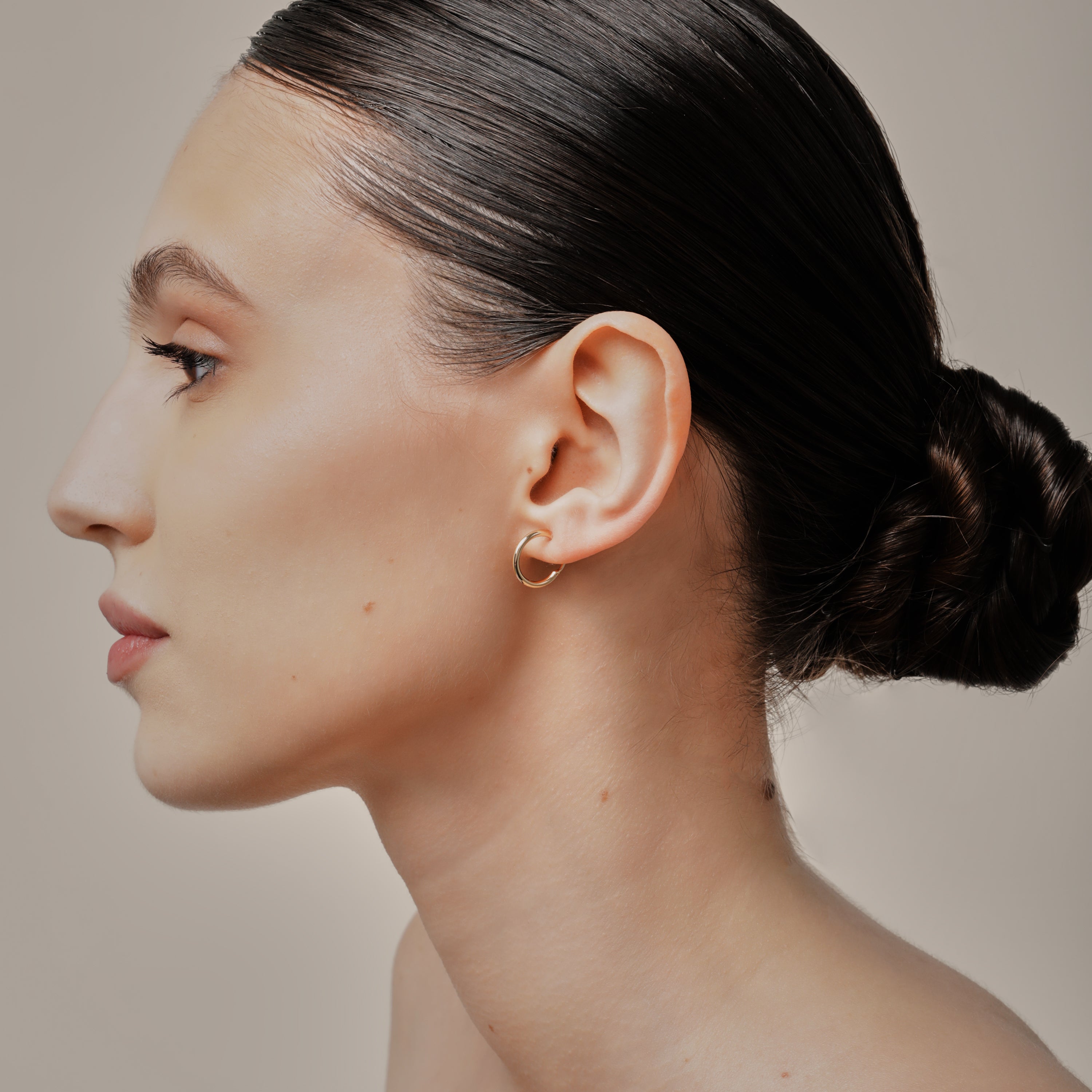 A model wearing the Tiny Hoop Clip On Earrings in Gold offer a Mosquito Coil Clip-On Closure, designed for comfort and versatility. Perfect for various ear types, they provide a secure hold and comfortable wear for 24 hours.