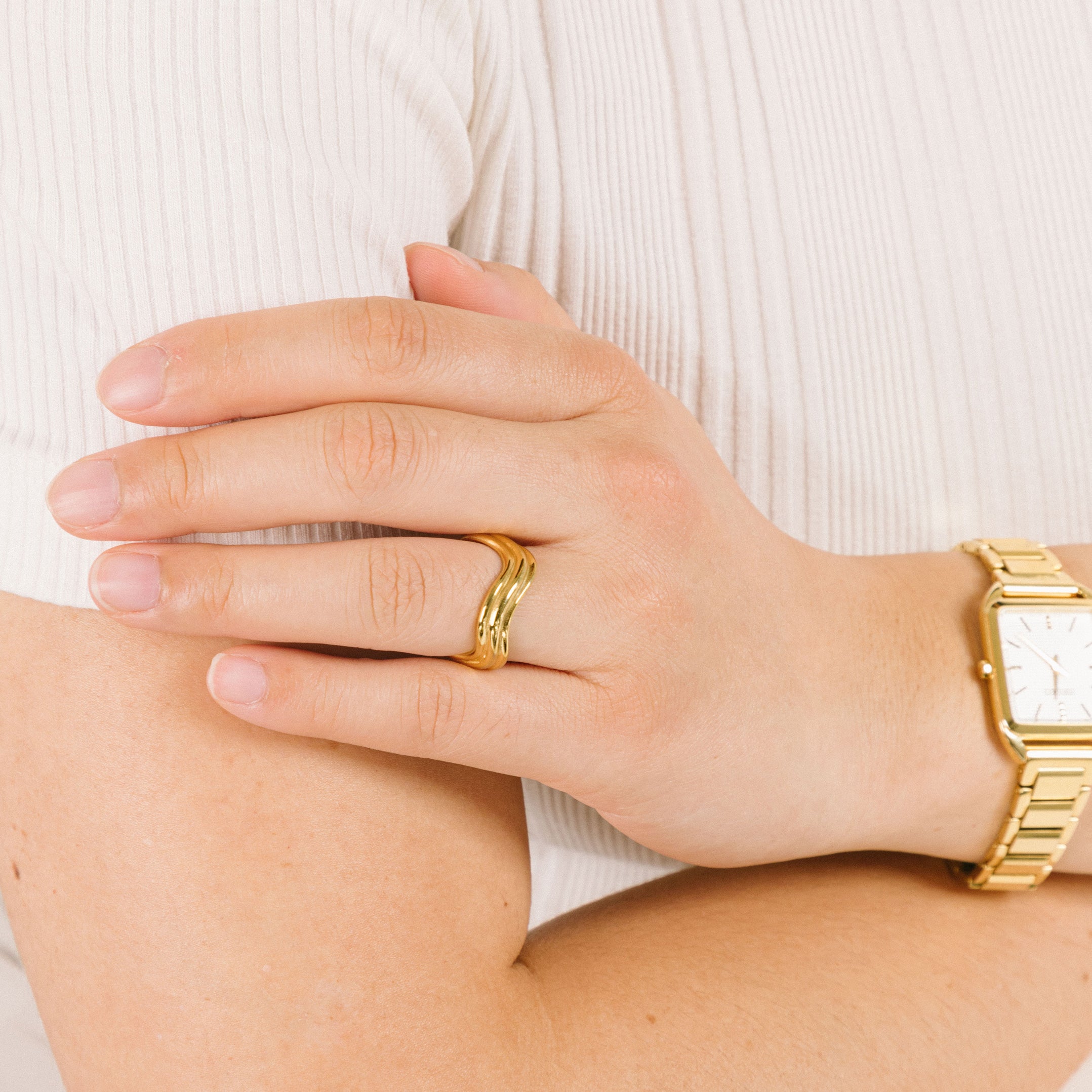 A model wearing the Triple Wave Ring features a non-tarnish, water-resistant stainless steel core plated in 18K gold. This item is sold as one item and cannot be adjusted.
