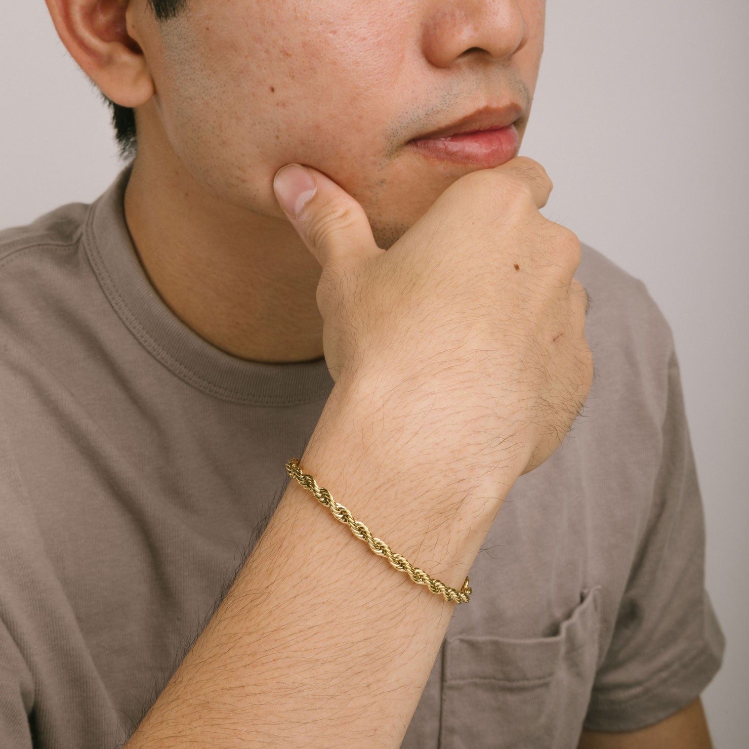 A model wearing the Twist Rope Chain Bracelet in Gold is crafted with high-quality 18K Gold plating, and features a length of 18cm and width of 4mm. Enjoy the additional benefits of its non-tarnish and water-resistant properties.