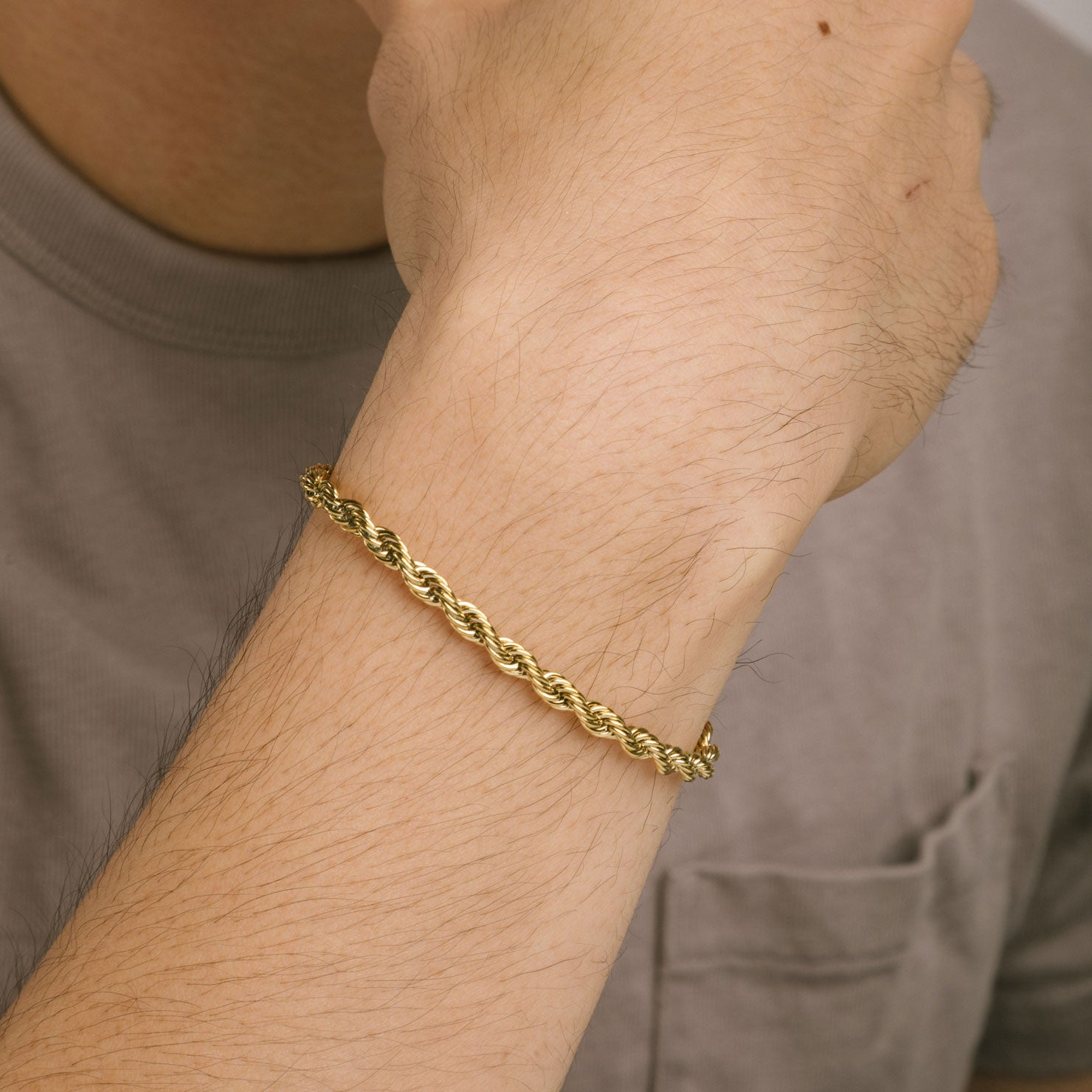 A model wearing the Twist Rope Chain Bracelet in Gold is crafted with high-quality 18K Gold plating, and features a length of 18cm and width of 4mm. Enjoy the additional benefits of its non-tarnish and water-resistant properties.