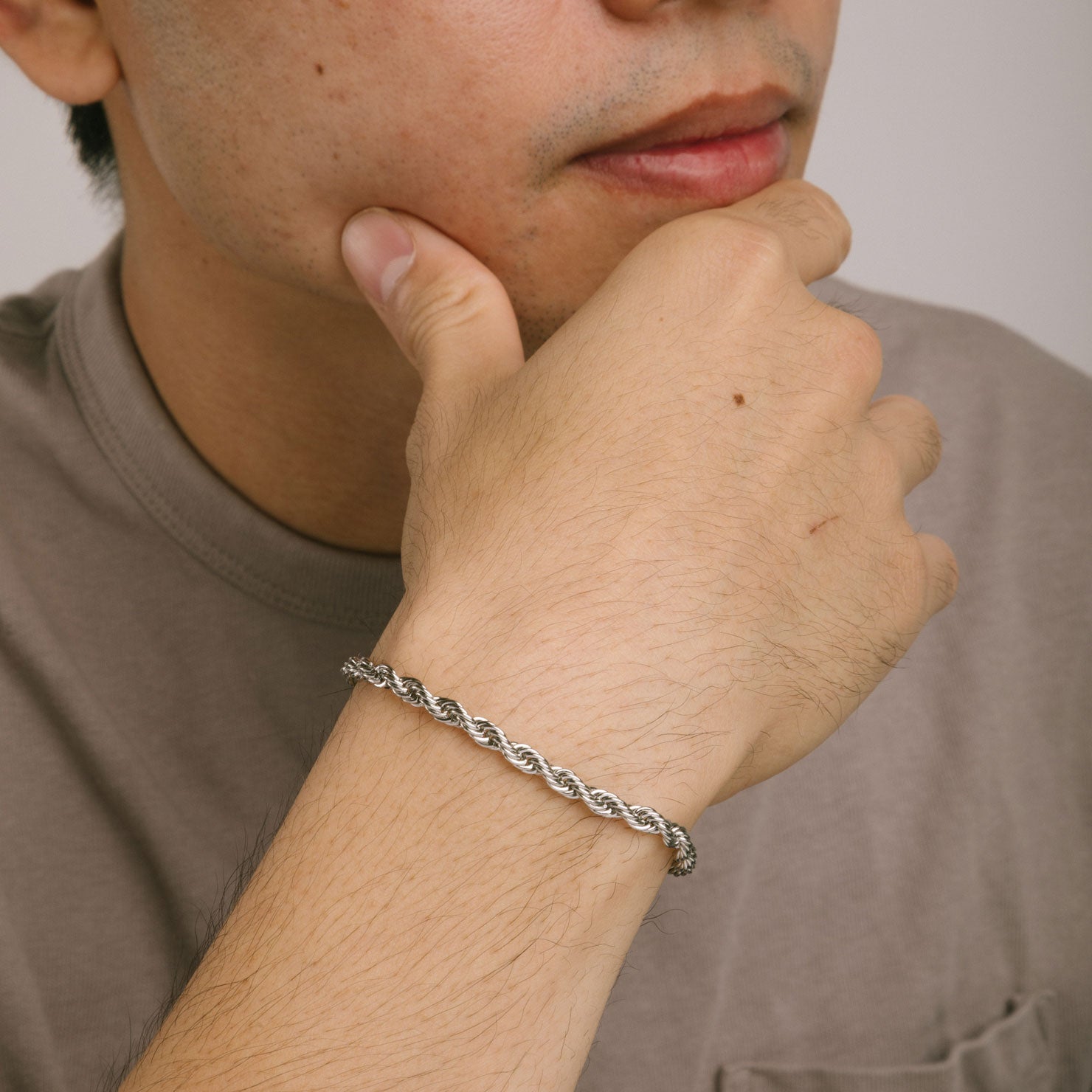 A model wearing the Twist Rope Chain Bracelet in Silver is crafted from non-tarnish and water-resistant stainless steel, with dimensions of 18 cm in length and 4 mm in width.