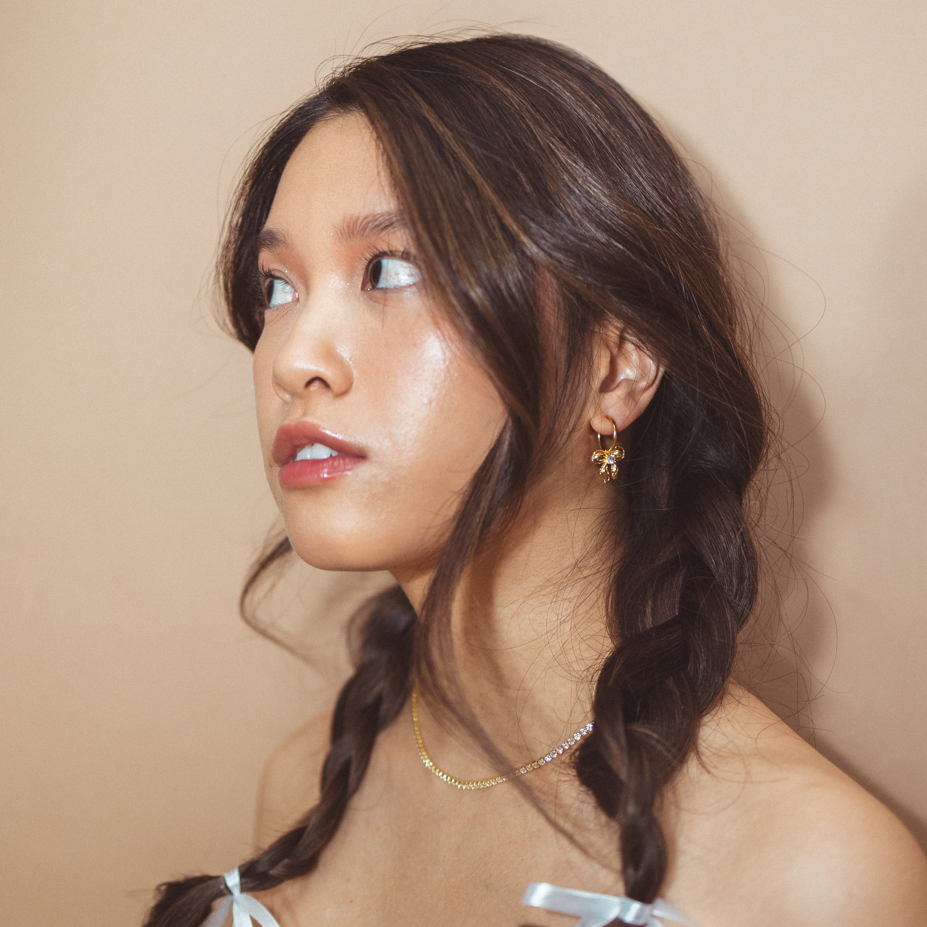 A model wearing the Ares Clip On Earrings. The sliding spring closure allows for easy adjustment to fit any ear thickness, while the gold tone copper alloy provides a secure hold. Perfect for stretched/healing ears or small/thin earlobes.