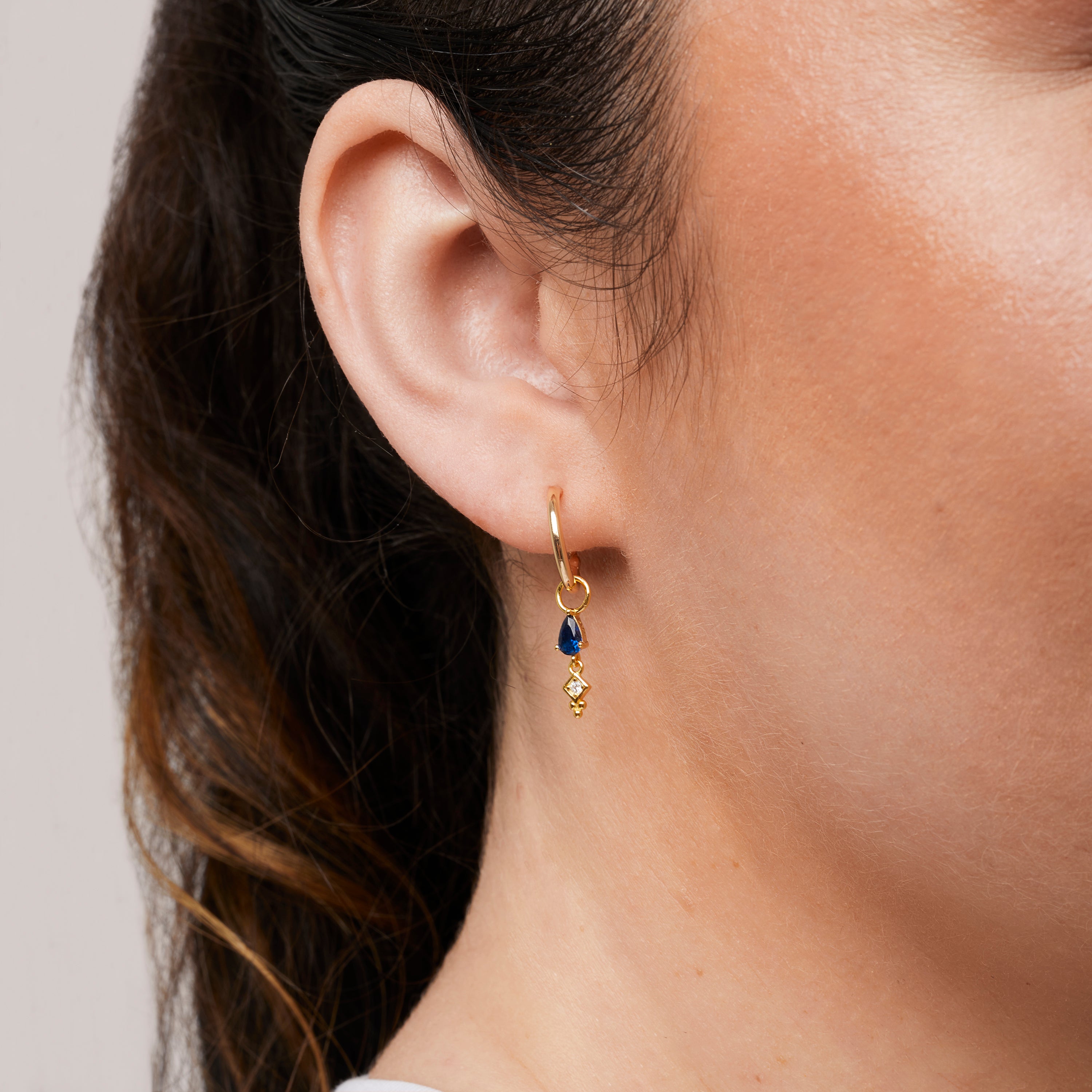 A model wearing the Deco Hoop Charms in Gold are made with high-quality materials, including 18K gold plating over 925 Sterling Silver. These charms are both non-tarnish and water resistant. The perfect combination of style and durability.