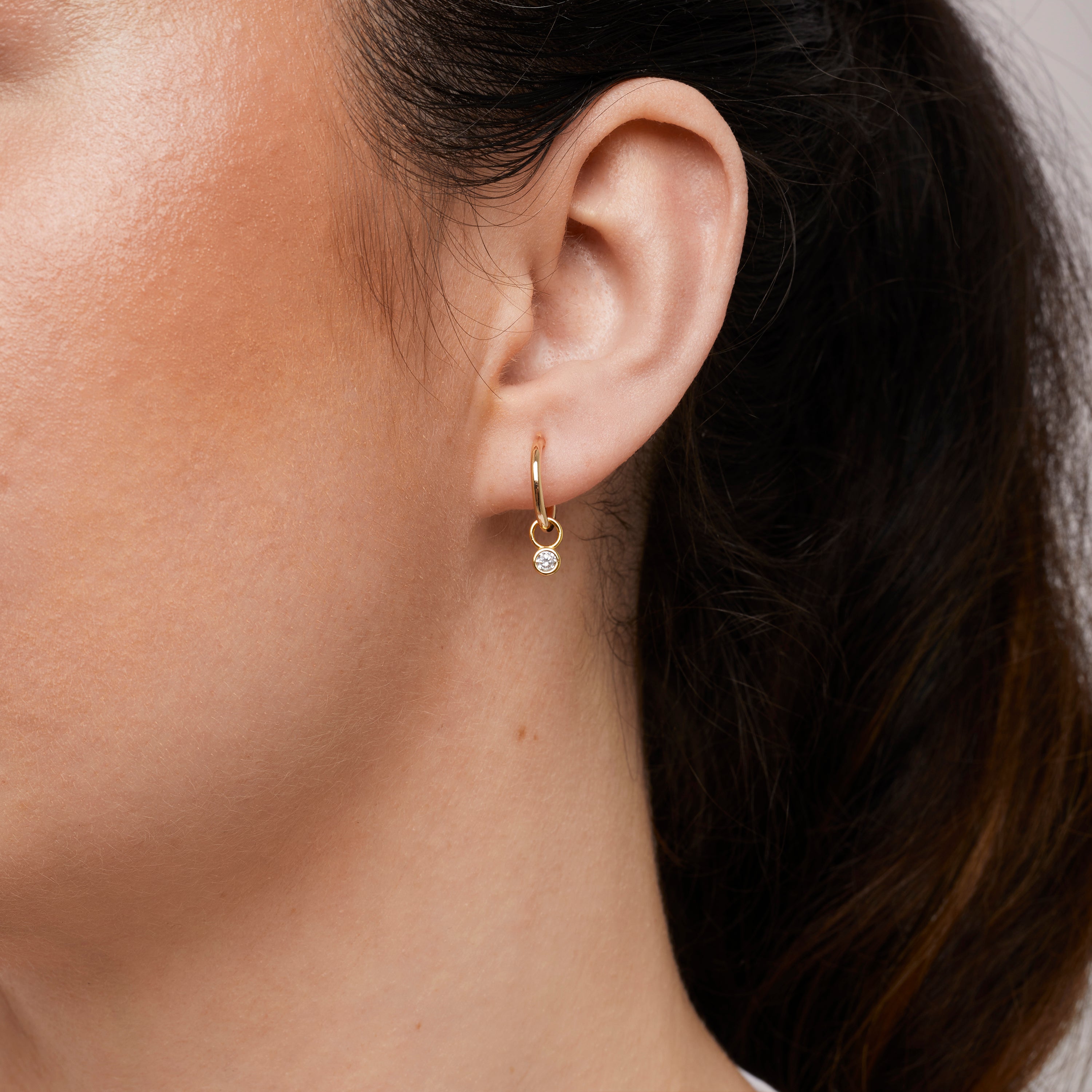 A model wearing the Mini Gemstone Hoop Charms are made with high-quality materials, including 18K gold plating over 925 Sterling Silver. These charms are both non-tarnish and water resistant. The perfect combination of style and durability.