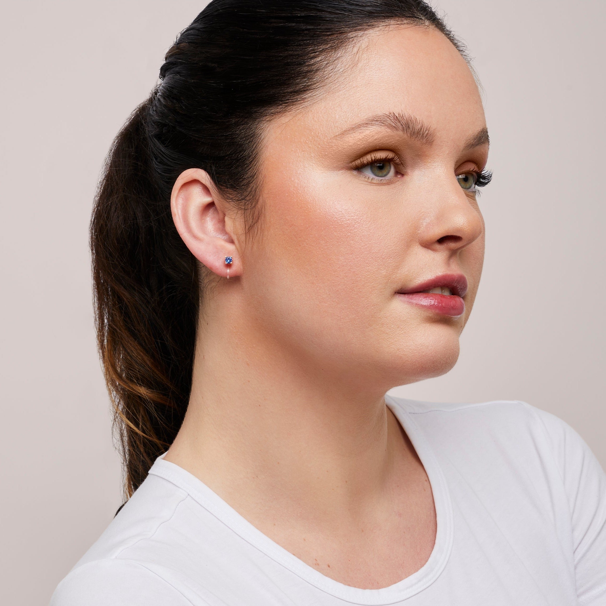 A model wearing the Mini Stud Clip-On Earrings possess a resin clip-on closure, making them suitable for a variety of ear types and offering a medium secure hold for comfortable wear lasting 8-12 hours. Please note that this item is a single pair.