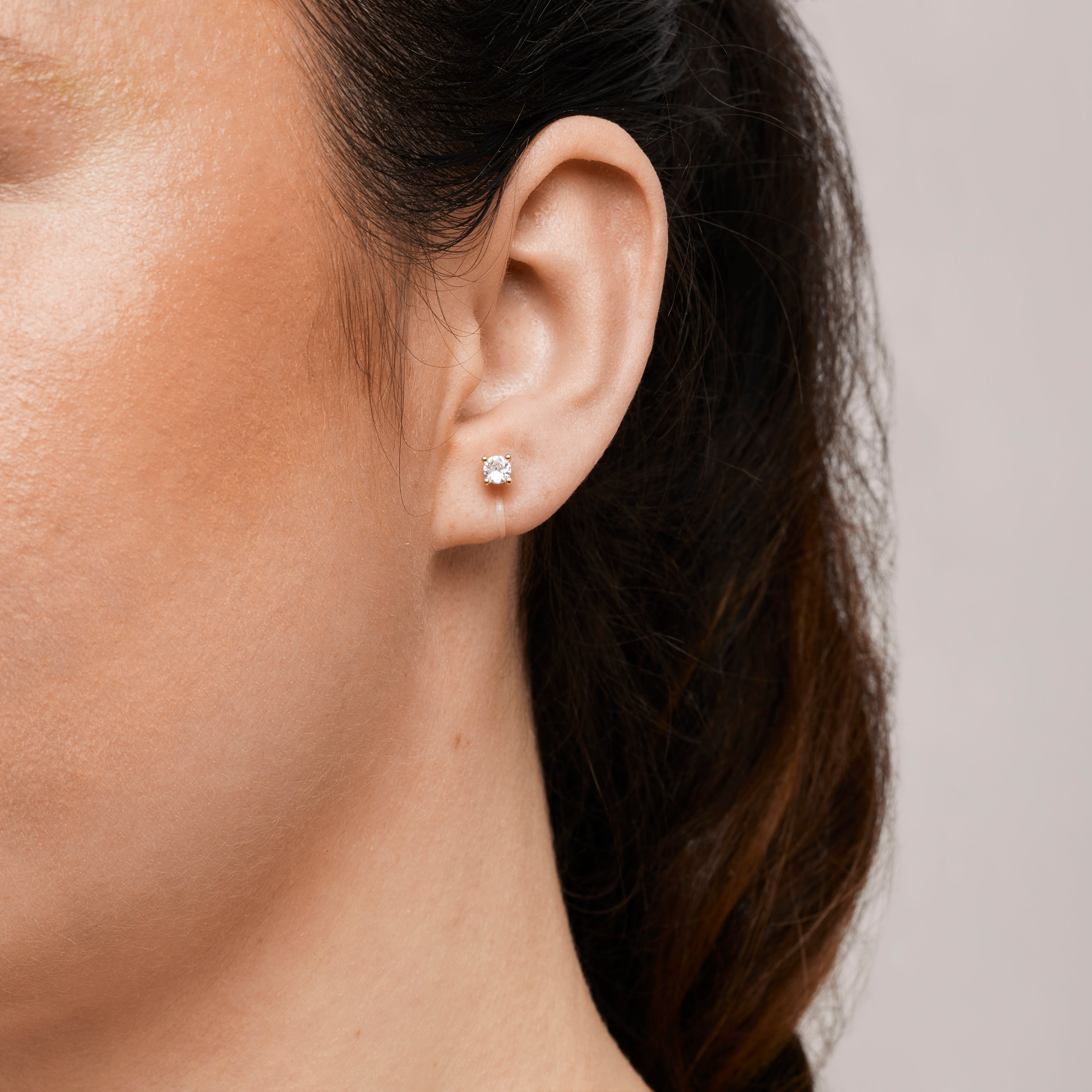 A model wearing the Mini Stud Clip-On Earrings possess a resin clip-on closure, making them suitable for a variety of ear types and offering a medium secure hold for comfortable wear lasting 8-12 hours. Please note that this item is a single pair.