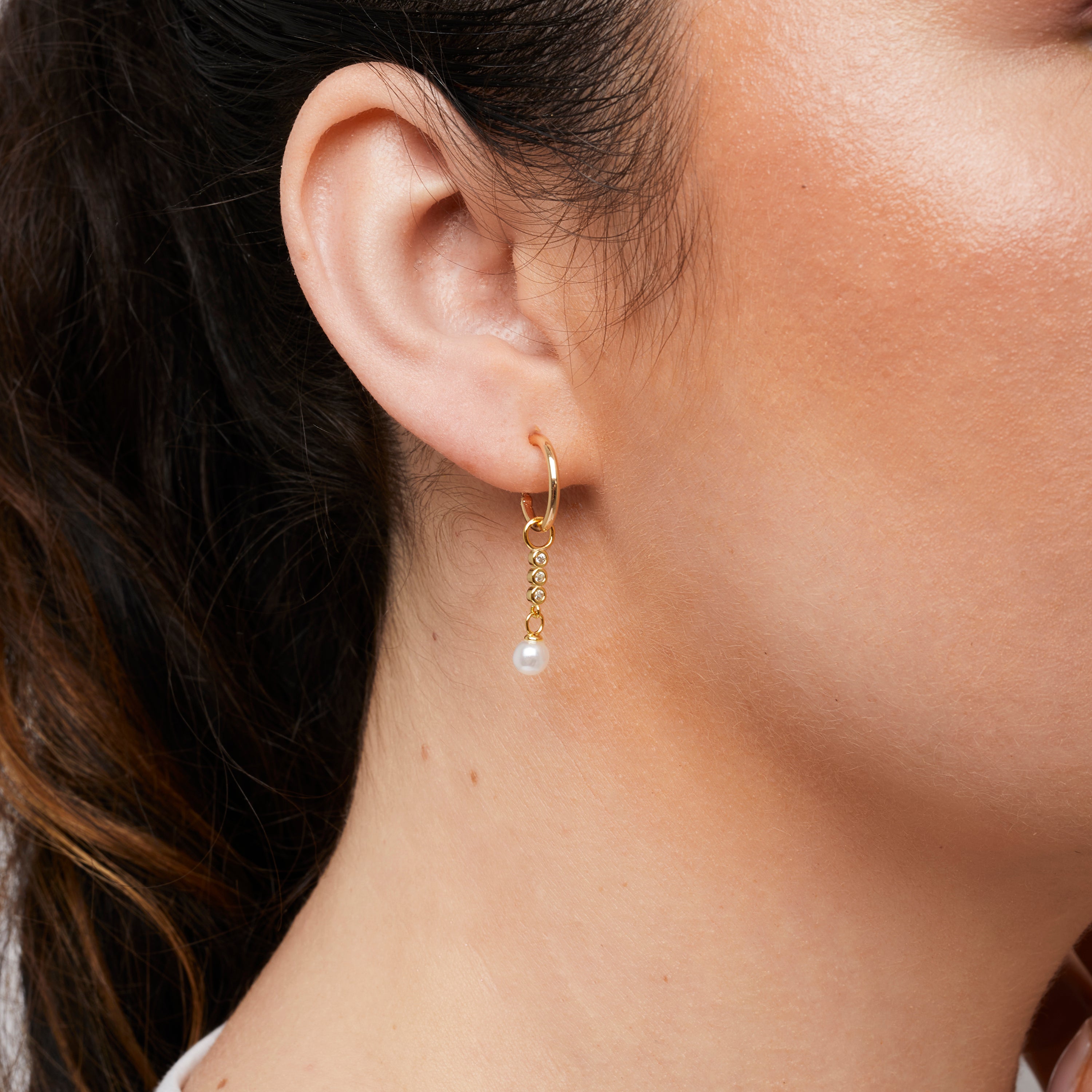 A model wearing the Pearl Dangle Hoop Charms are made with high-quality materials, including 18K gold plating over 925 Sterling Silver. These charms are both non-tarnish and water resistant. The perfect combination of style and durability.