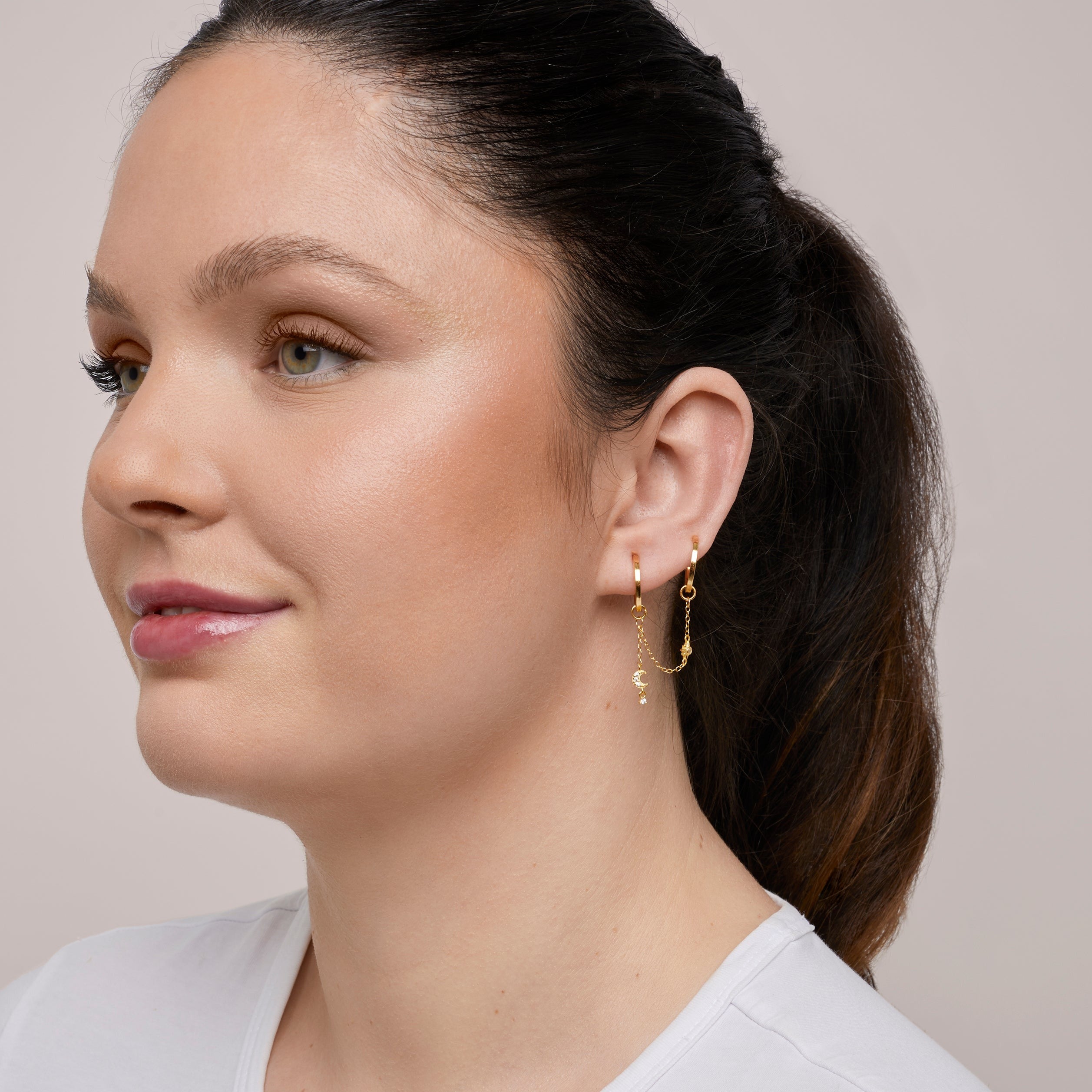 A model wearing the Single Celestial Hoop Chain are made with high-quality materials, including 18K gold plating over 925 Sterling Silver. These charms are both non-tarnish and water resistant. The perfect combination of style and durability.