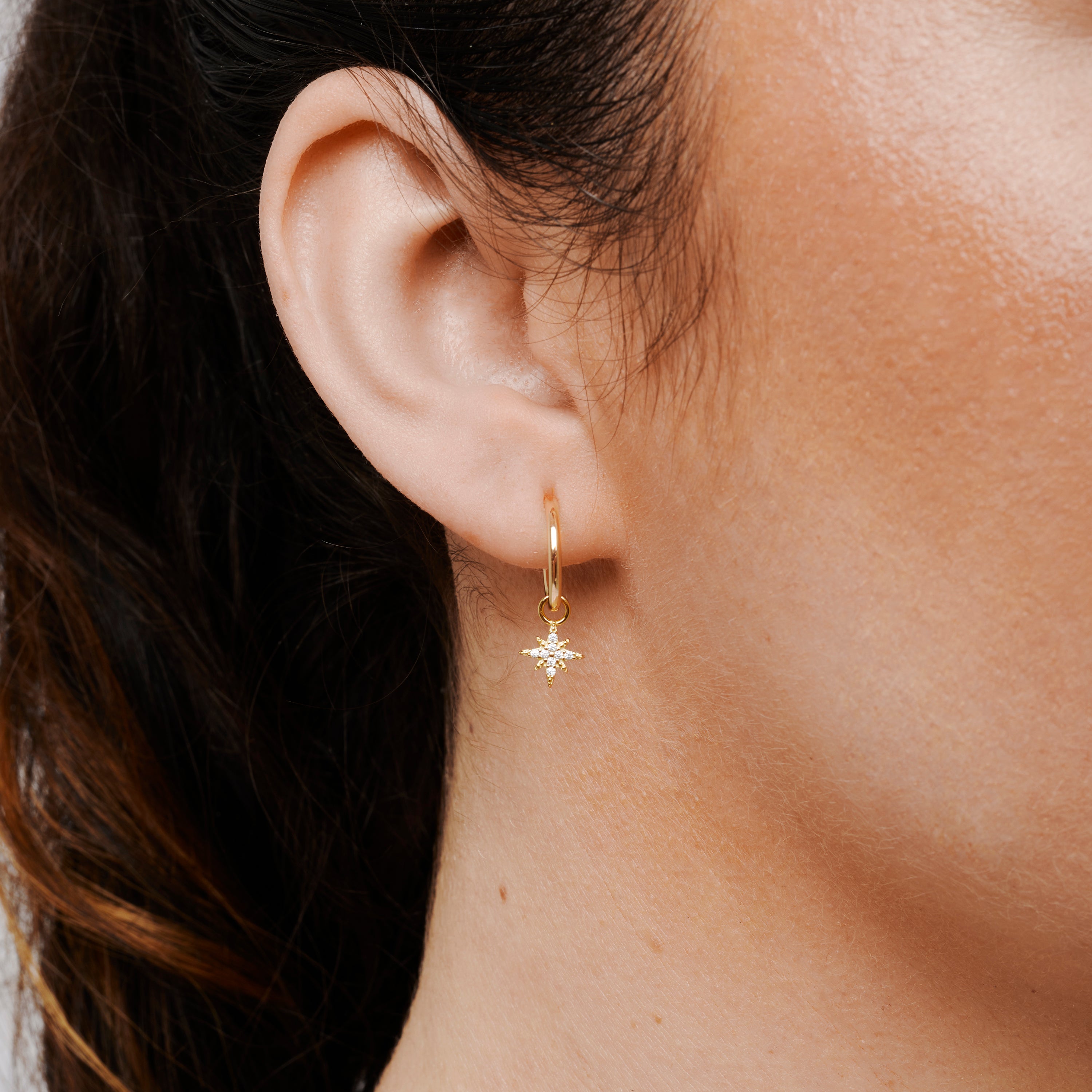 A model wearing the Star Hoop Charms in Gold are made with high-quality materials, including 18K gold plating over 925 Sterling Silver. These charms are both non-tarnish and water resistant. The perfect combination of style and durability.