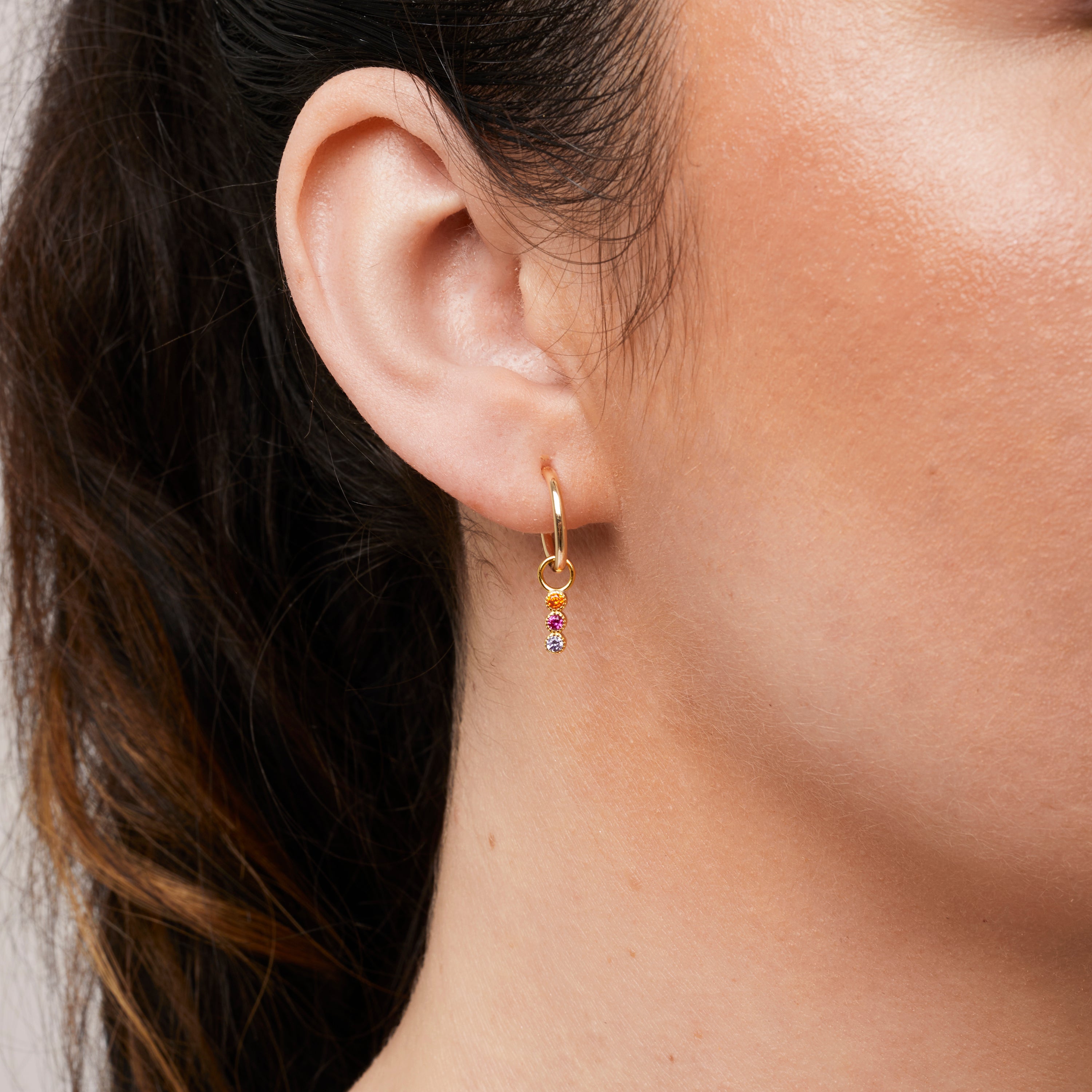 A model wearing the Sunset Hoop Charms are made with high-quality materials, including 18K gold plating over 925 Sterling Silver. These charms are both non-tarnish and water resistant. The perfect combination of style and durability.