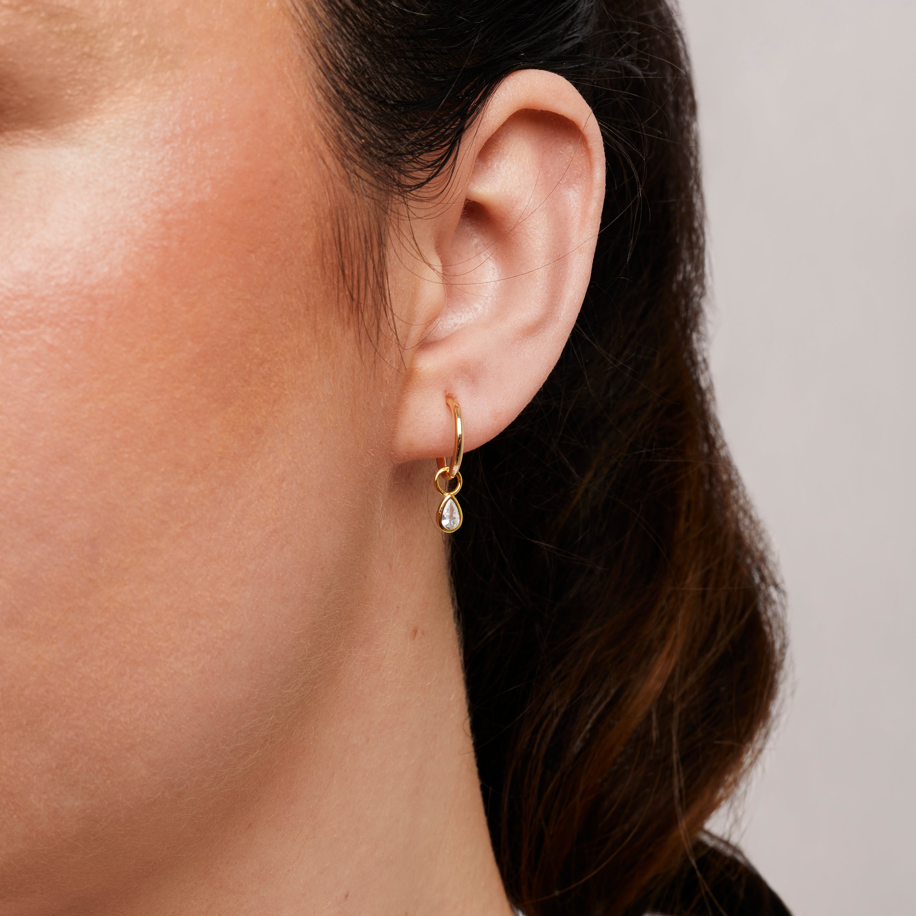A model wearing the Teardrop Hoop Charms are made with high-quality materials, including 18K gold plating over 925 Sterling Silver. These charms are both non-tarnish and water resistant. The perfect combination of style and durability.